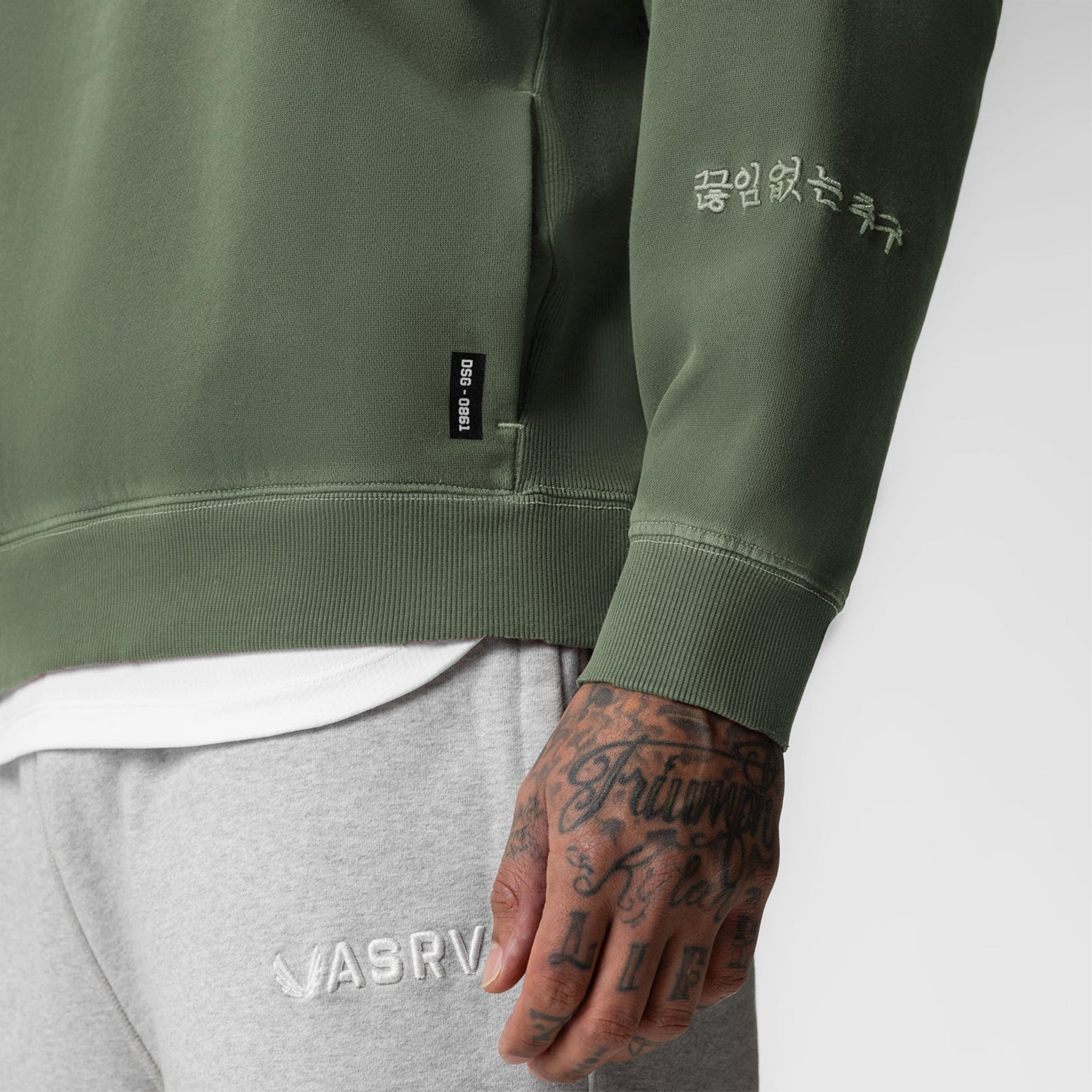 Tech Essential Distressed Crewneck in faded olive worn by model, detail view of sleeve and chest