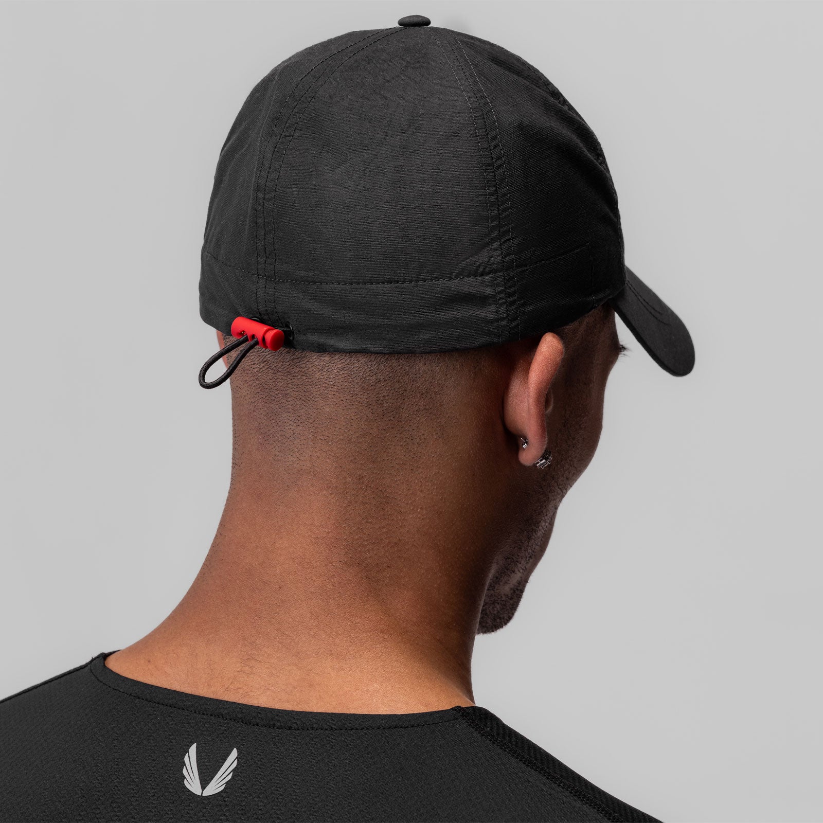 Weather-Ready Cinch Hat in black worn on model, back view showing red drawstring detail