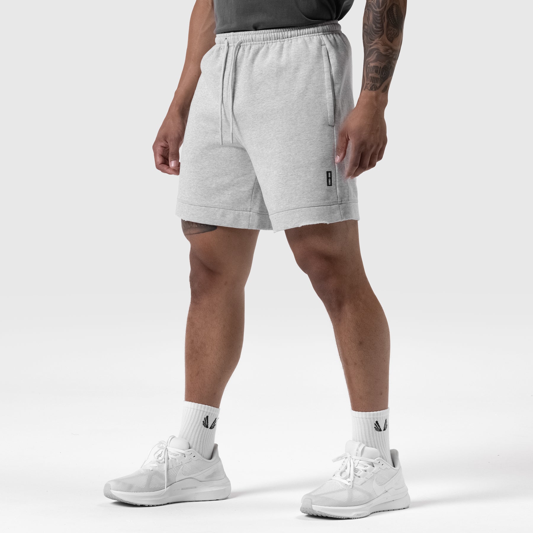 Tech Essential Sweat Short in heather grey, worn by model with white sneakers and socks
