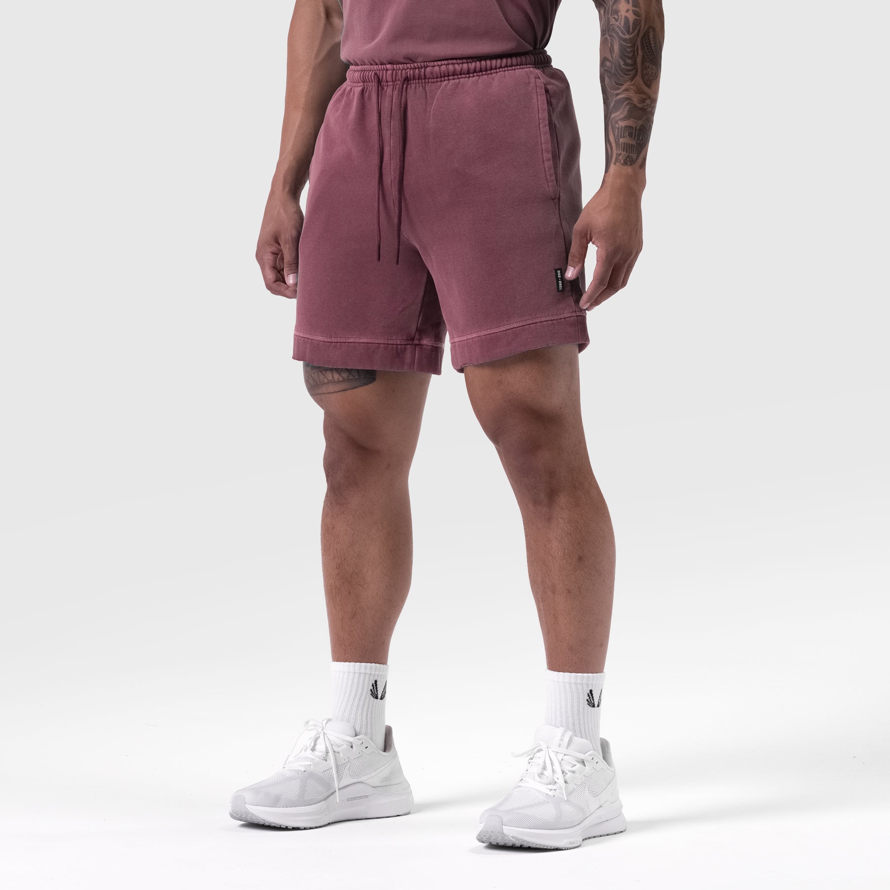 Tech Essential Sweat Short in faded crimson worn by model with white sneakers and white socks, front view