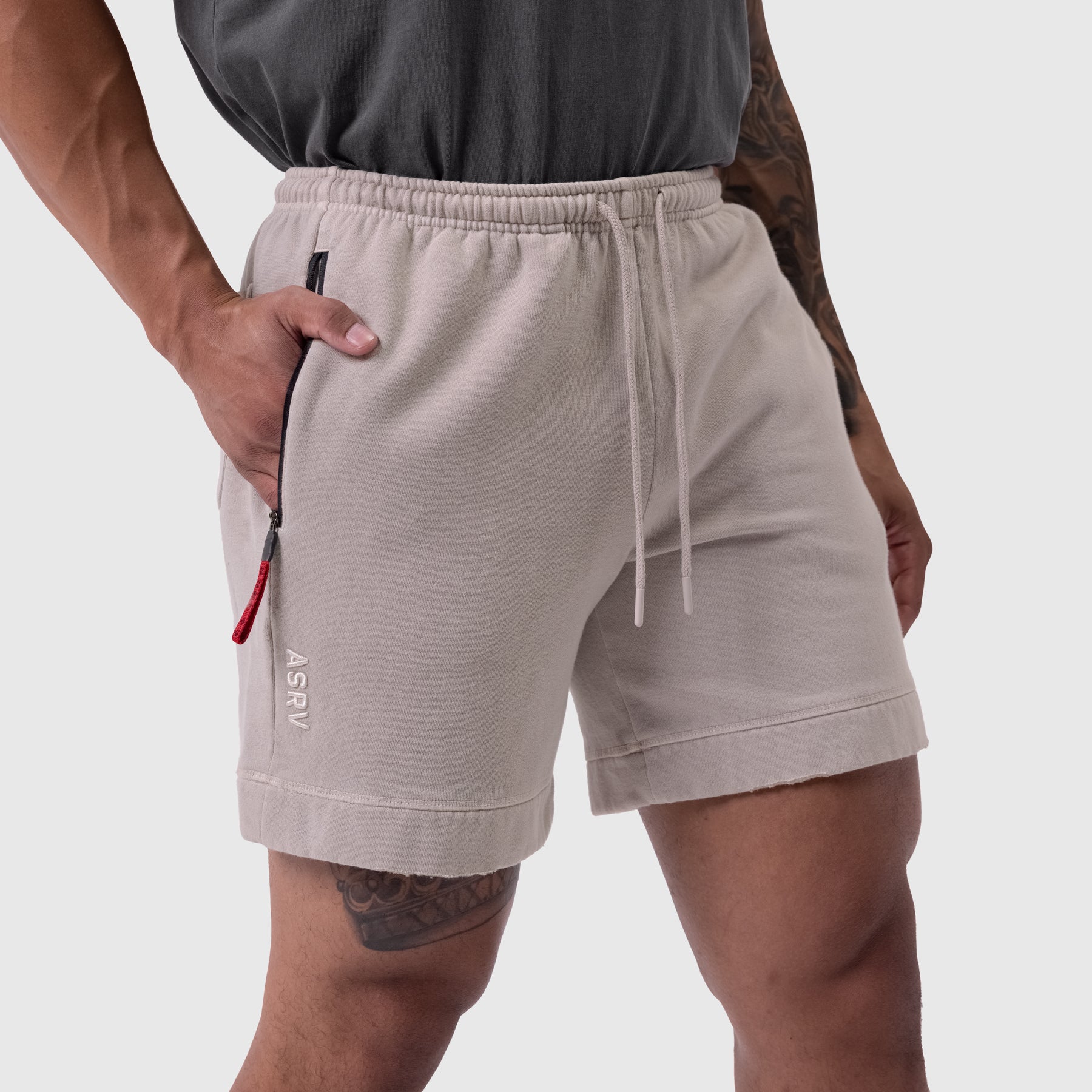 Tech Essential Sweat Short in faded chai worn by model, front view with hand in pocket