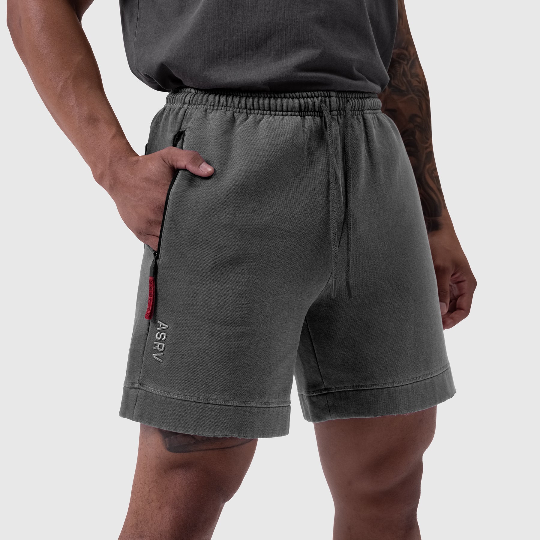 Tech Essential Sweat Short in faded grey worn by model, side view with hand in pocket