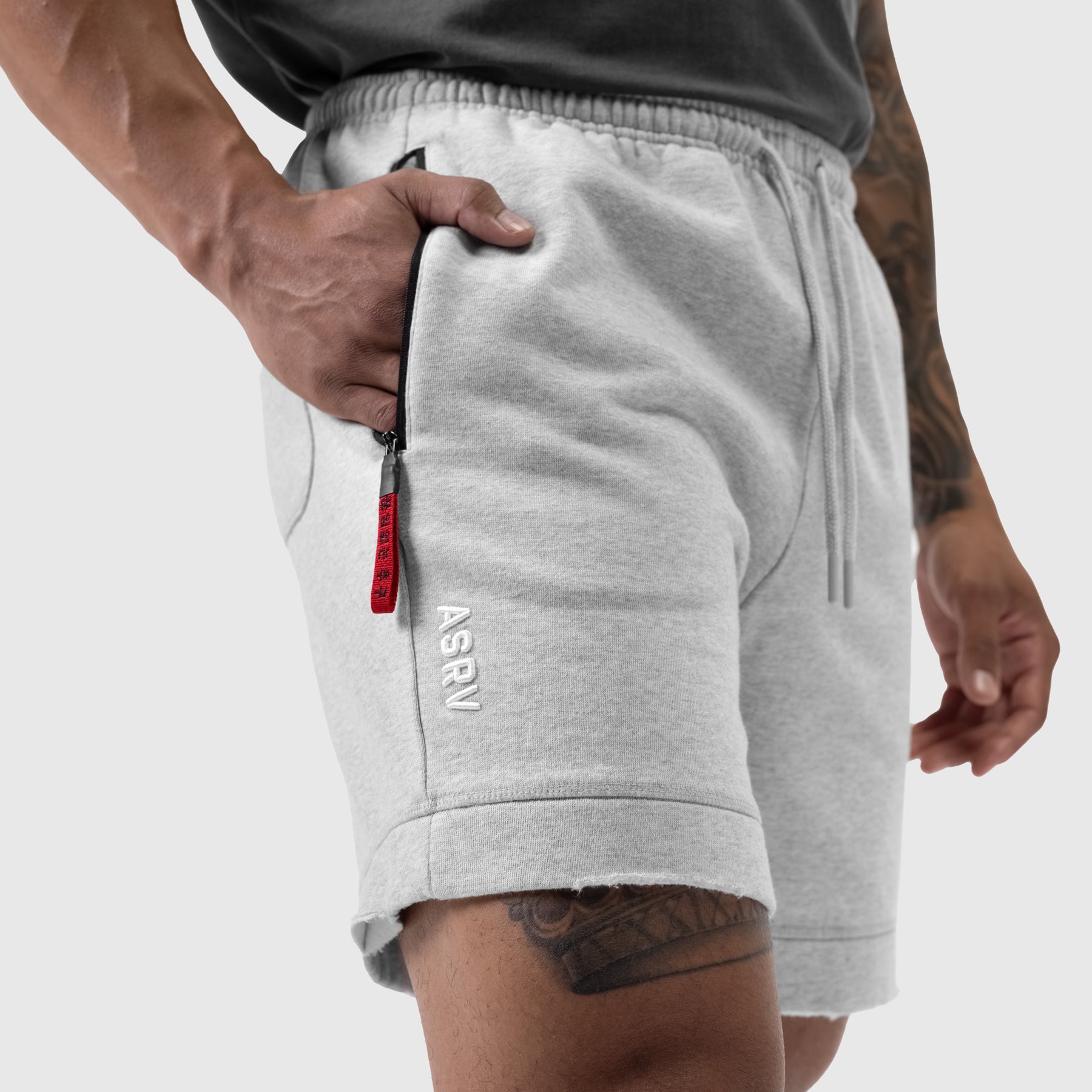 Tech Essential Sweat Short in heather grey worn by model, side view with hand in pocket