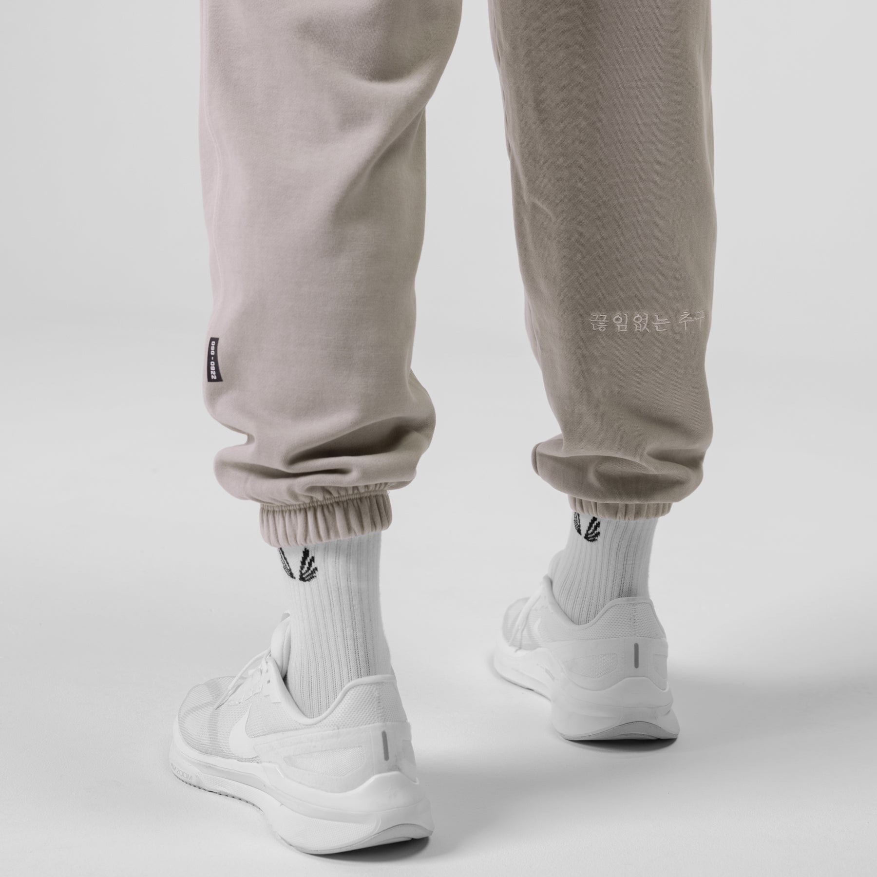 Tech Essential Sweats in Faded Chai worn with white socks and sneakers, calf-down view