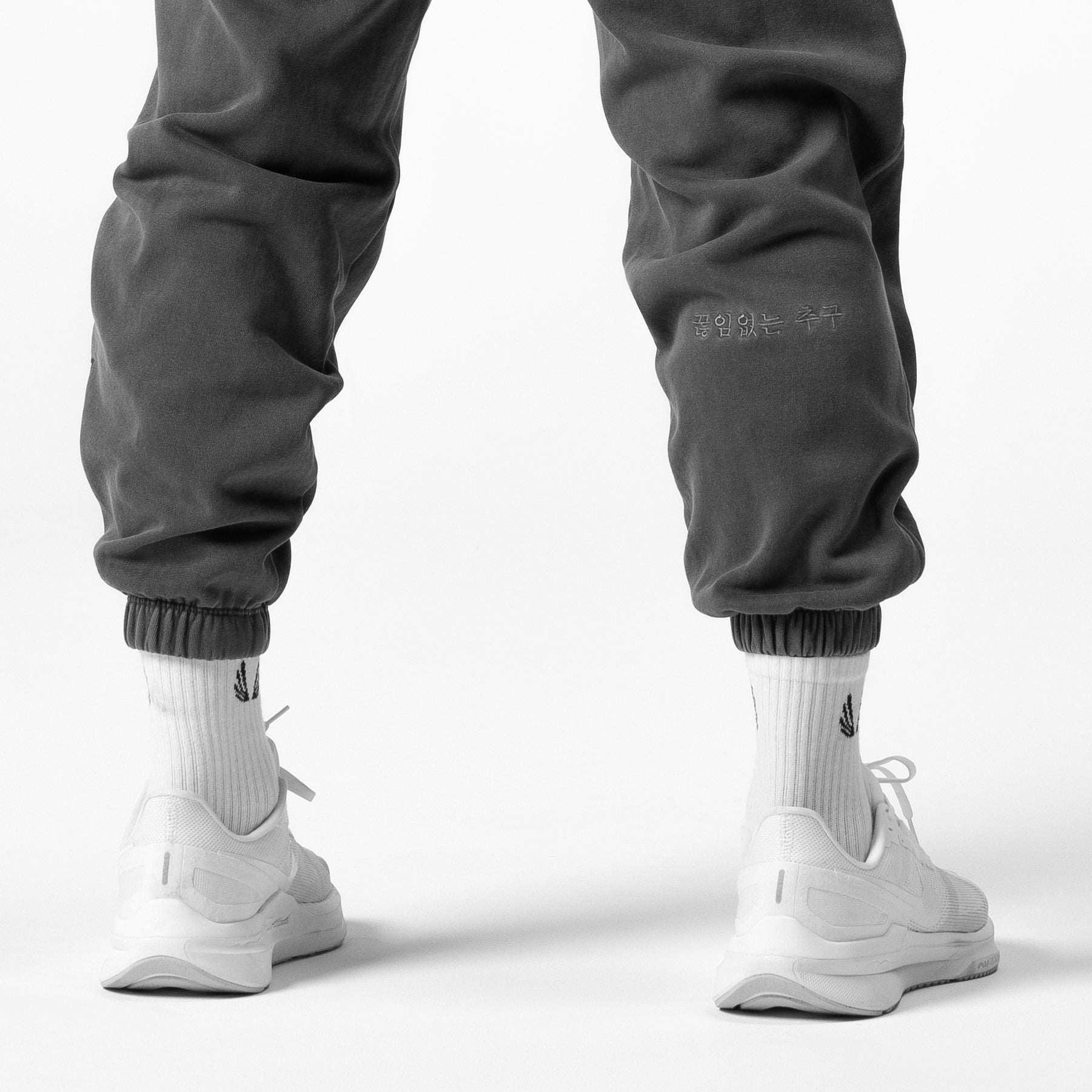 Tech Essential Sweats in faded grey worn with white socks and white sneakers, back view