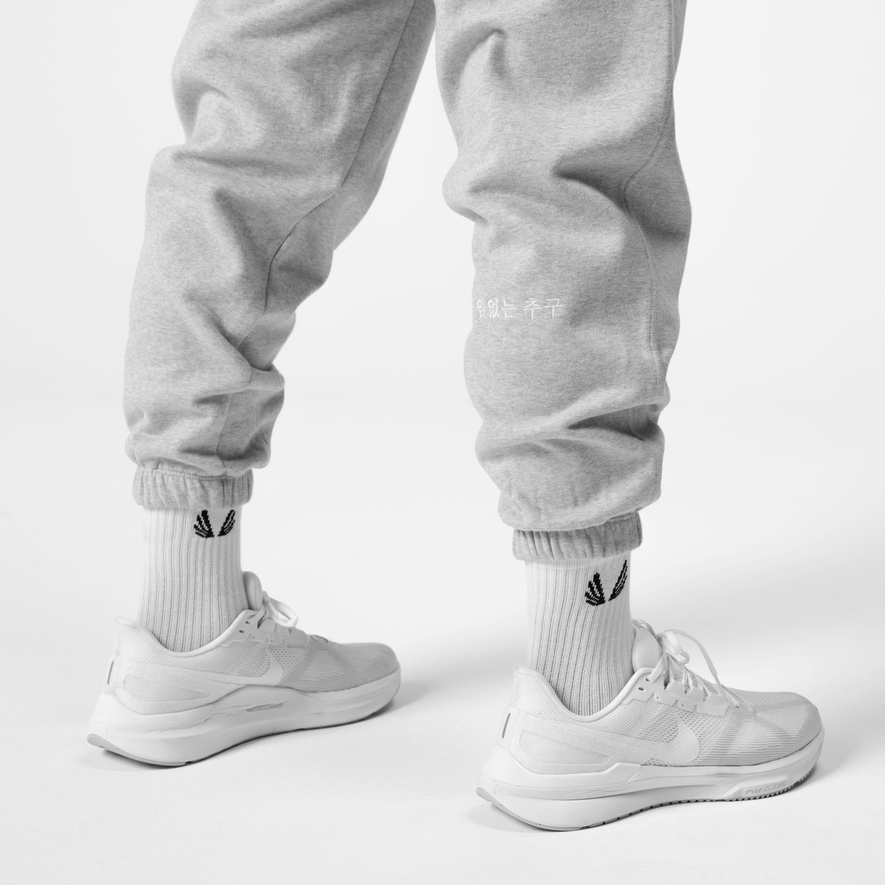 Tech Essential Sweats in heather grey, worn with white socks and sneakers, front view