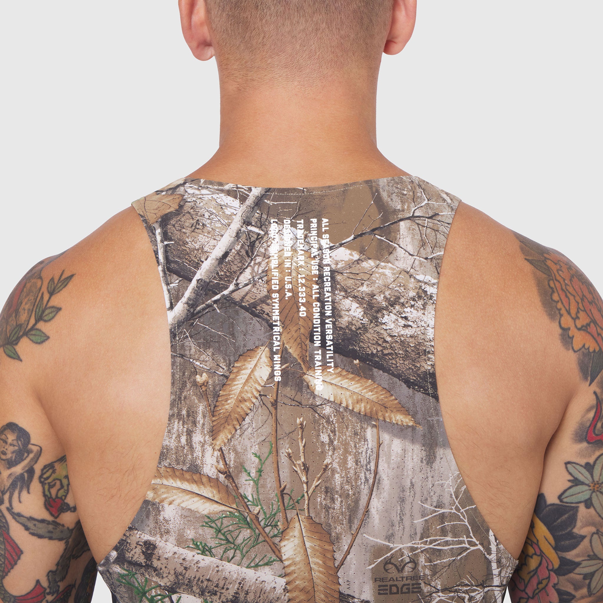 Laser-Vent Singlet Tank in Realtree Edge camo, back view on male model with visible tattoos