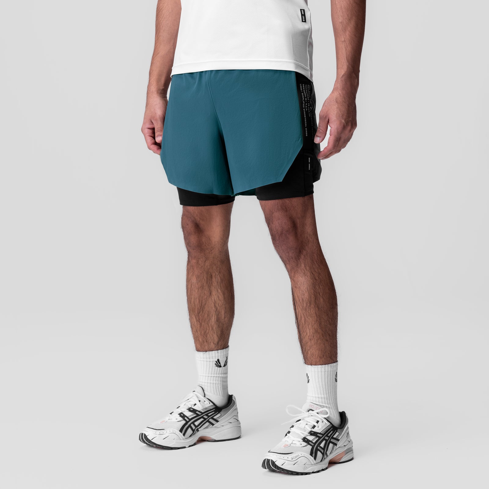 Aerotex Hybrid Liner Short in storm blue and black, worn by model with white socks and sneakers