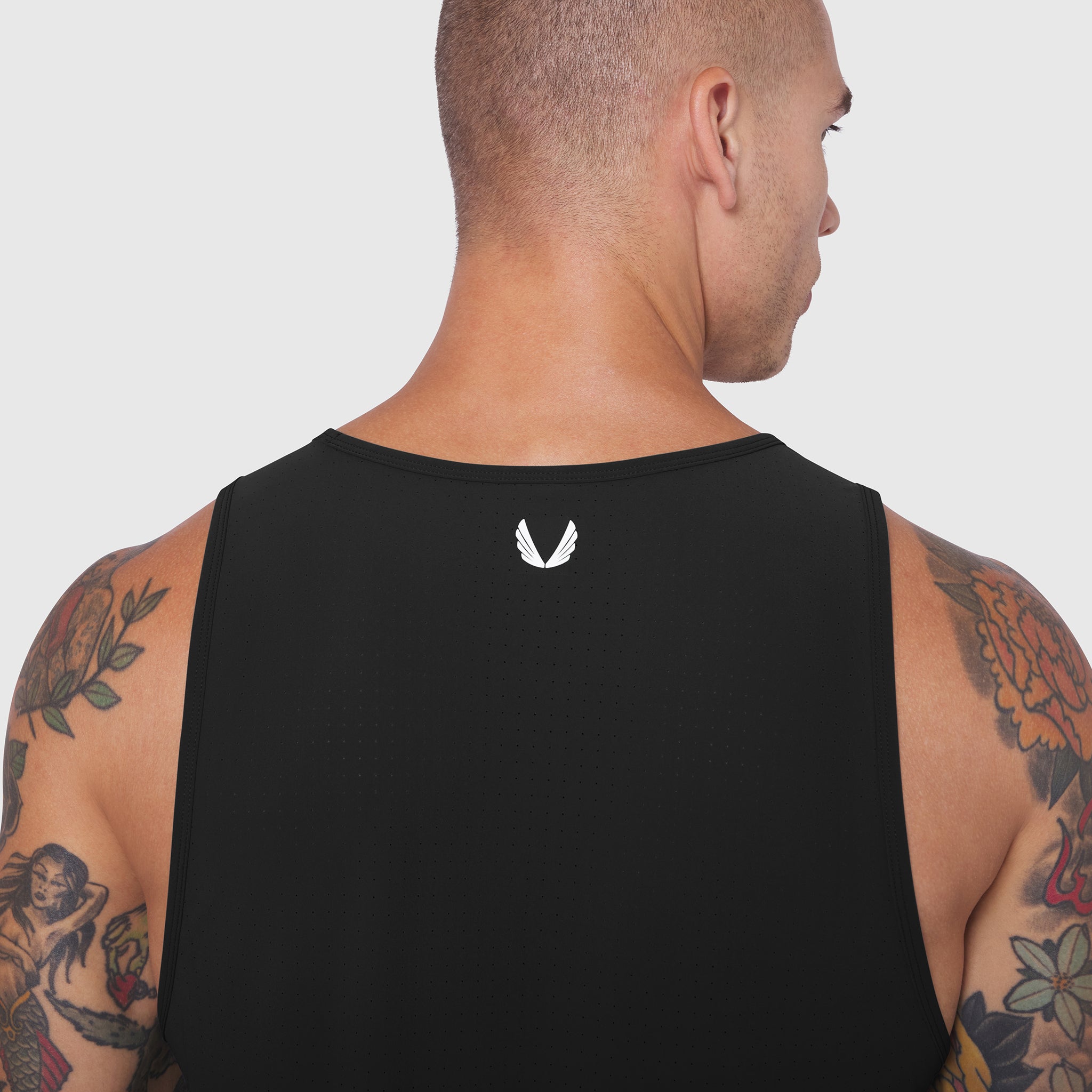 Black Laser-Vent Tank Top worn by tattooed man, rear view showing small logo