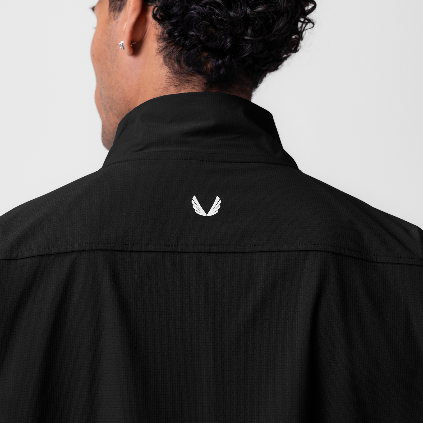 Black ripstop quarter zip jacket worn by model, back view showing white logo detail