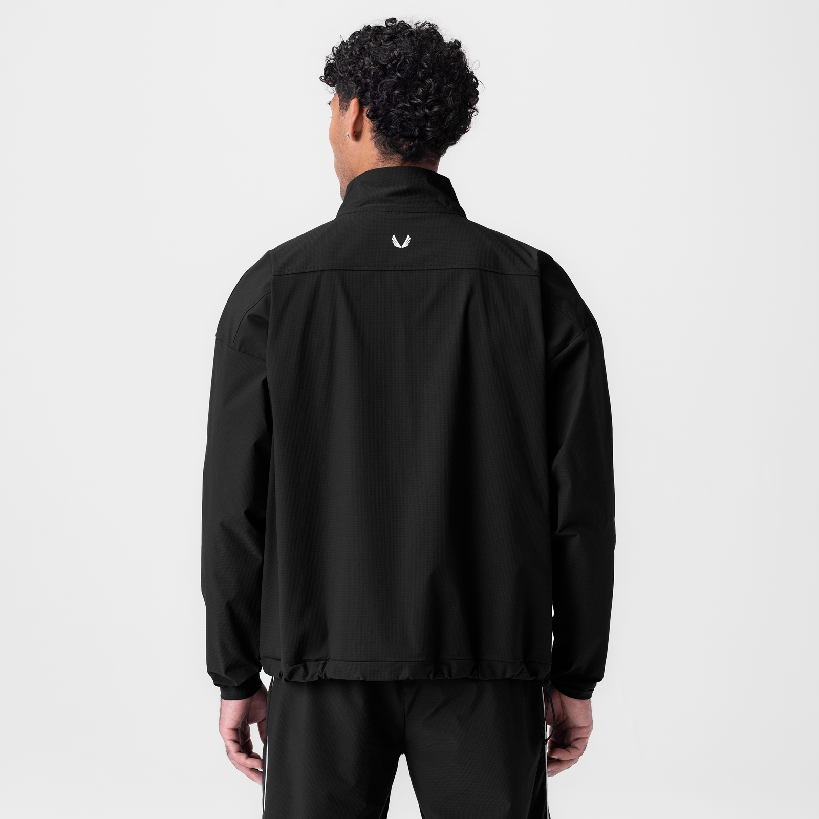 Black ripstop quarter zip jacket worn by model, back view