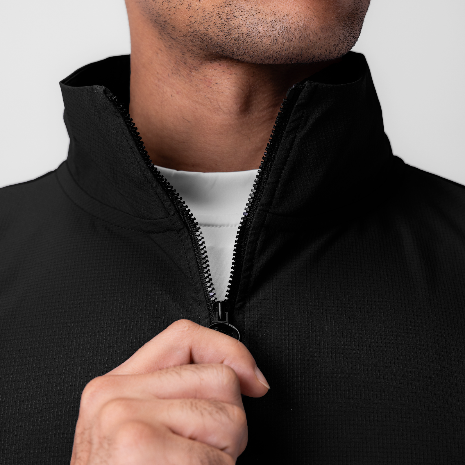 Black ripstop quarter zip jacket worn by model, front view with hand on zipper