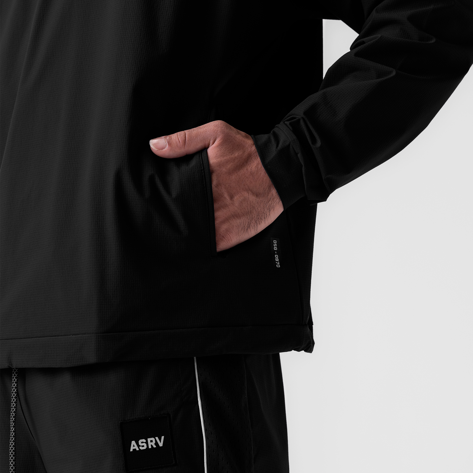 Black ripstop quarter zip jacket worn by model with hand in pocket, detail view