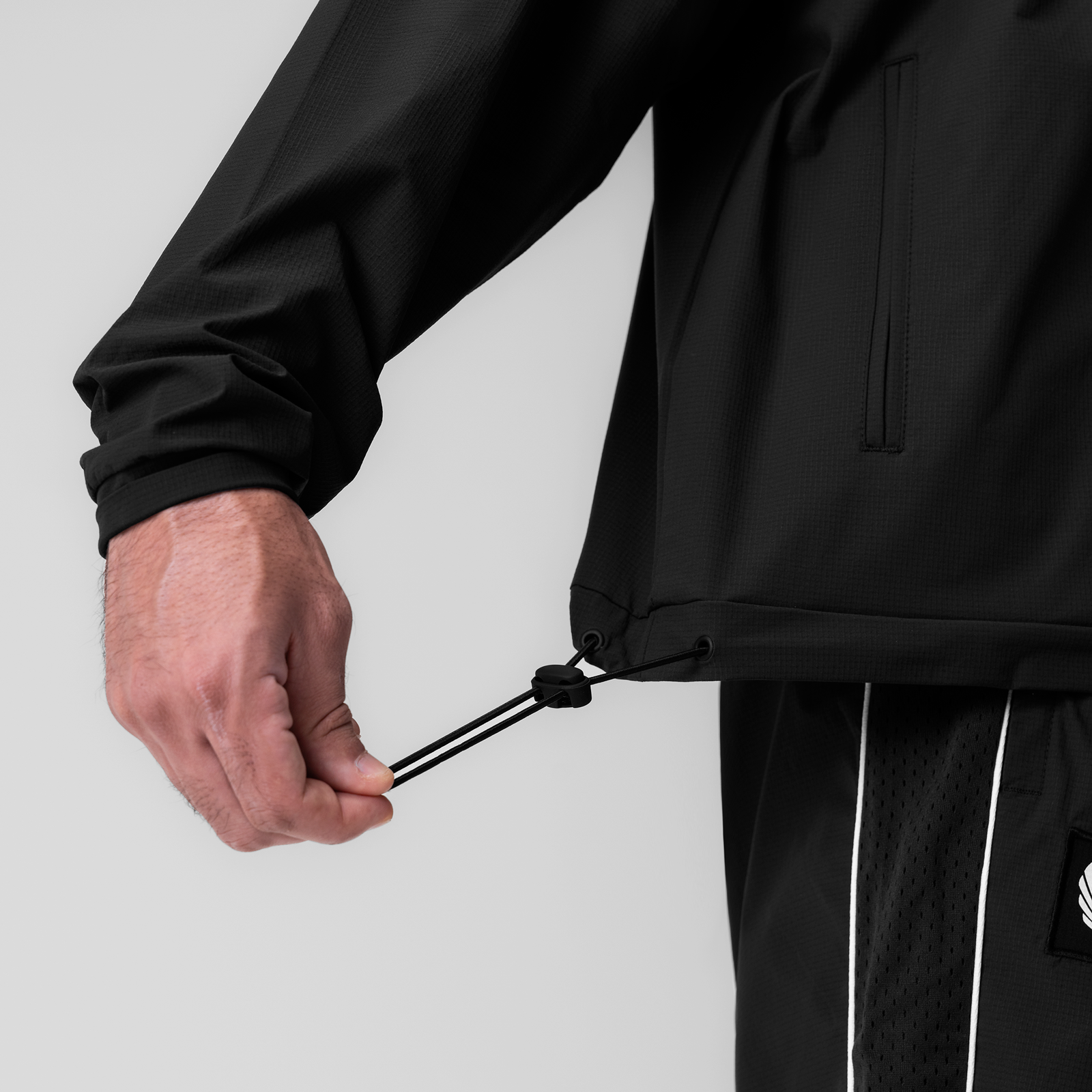 Black ripstop quarter zip jacket worn by model, detail of drawstring closure and sleeve