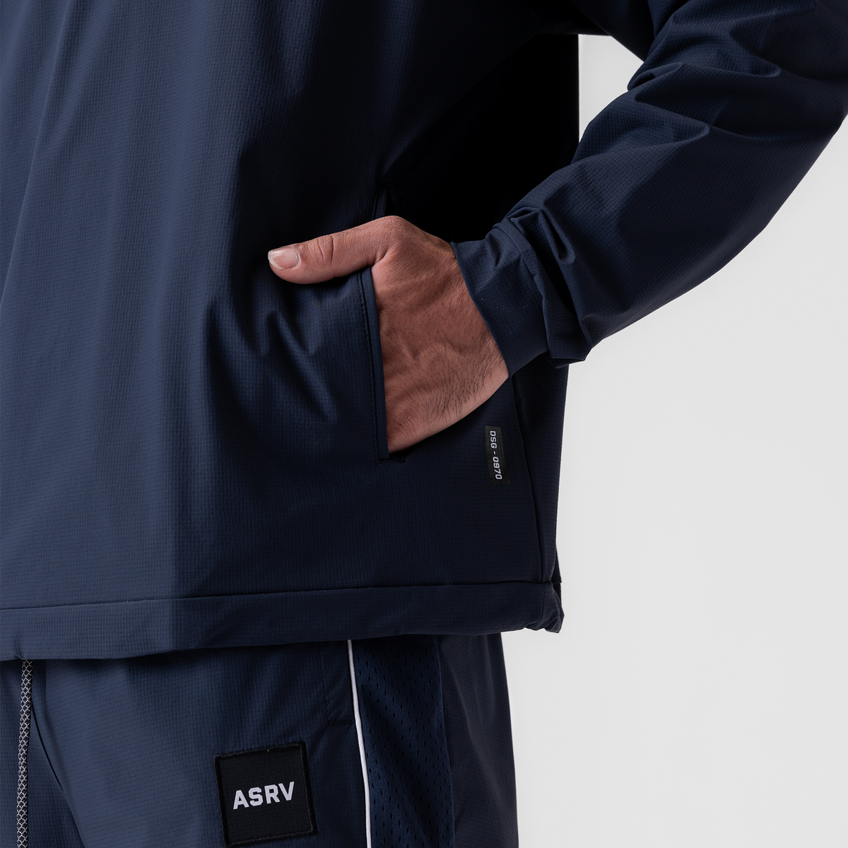 Navy ripstop quarter zip jacket worn by model with hand in pocket, detail view