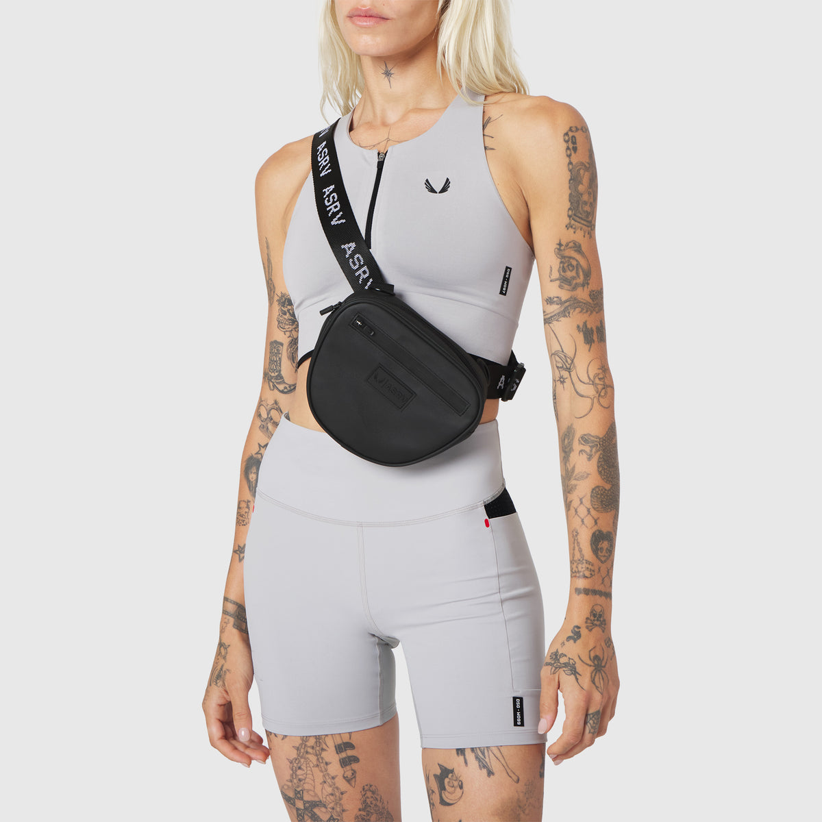 Trail Pack in black, worn as crossbody bag with sports bra and shorts