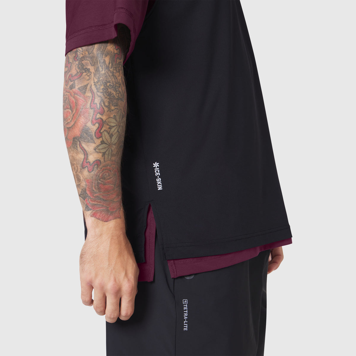 Reversible tee in merlot and black worn by model showing side view with tattooed arm visible