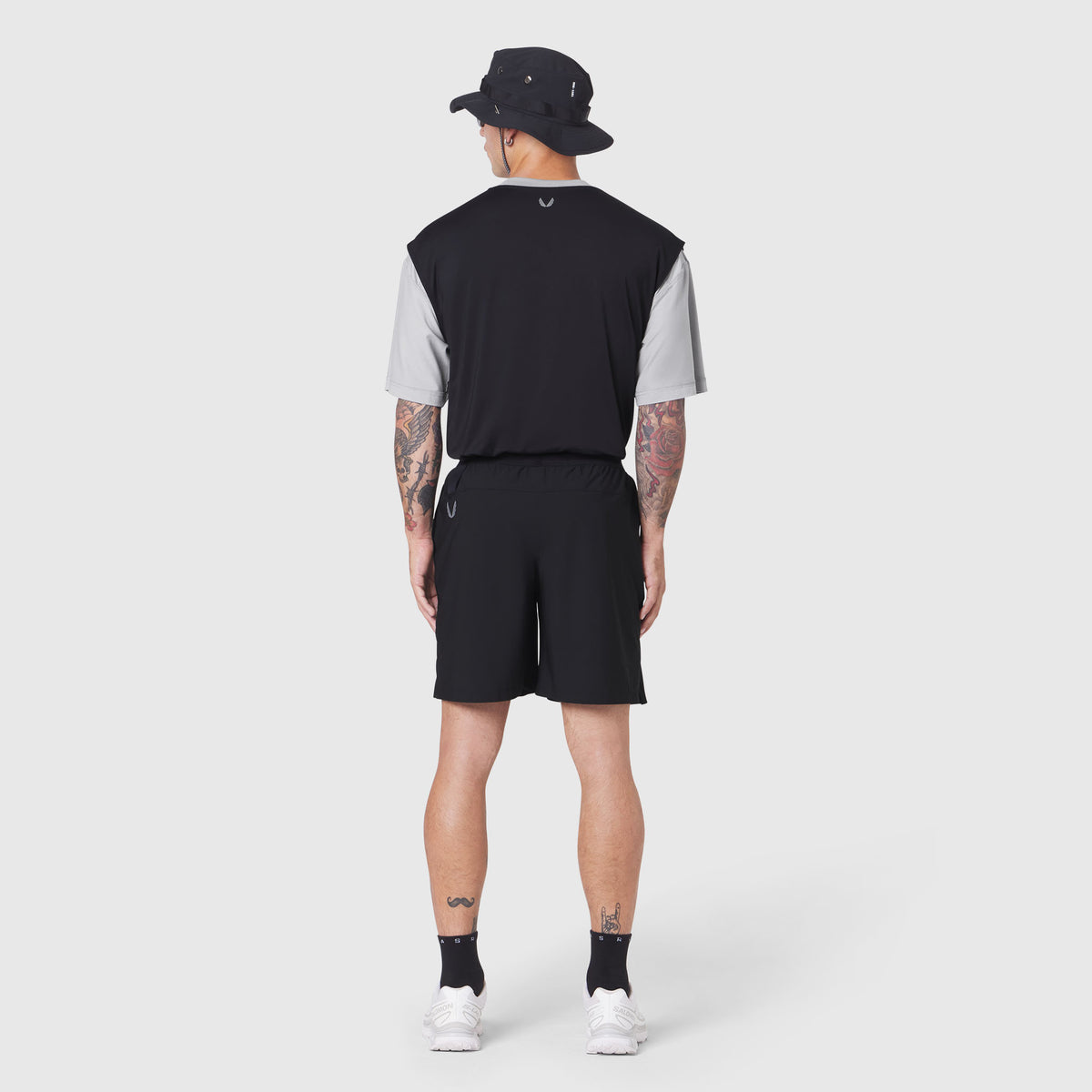 Reversible tee in black and grey worn by model from back, paired with black shorts and bucket hat