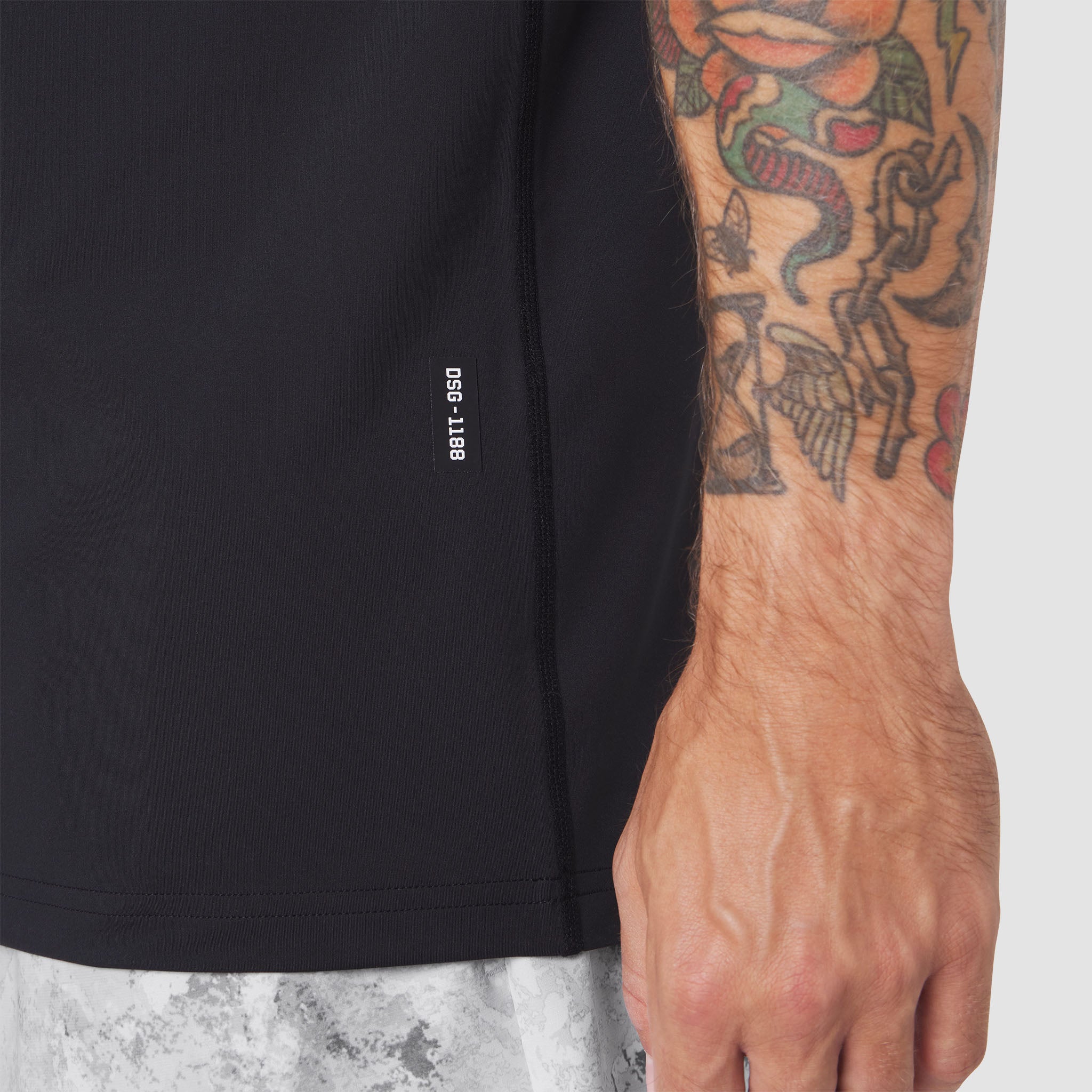Warpflexx-Lite® Training Tank in black, worn by model showing side view with tattooed arm