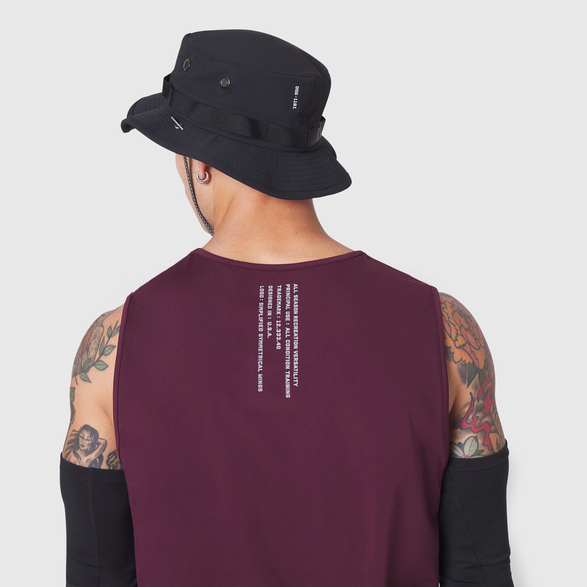 Warpflexx-Lite Training Tank in merlot, back view on model with tattoos wearing black bucket hat