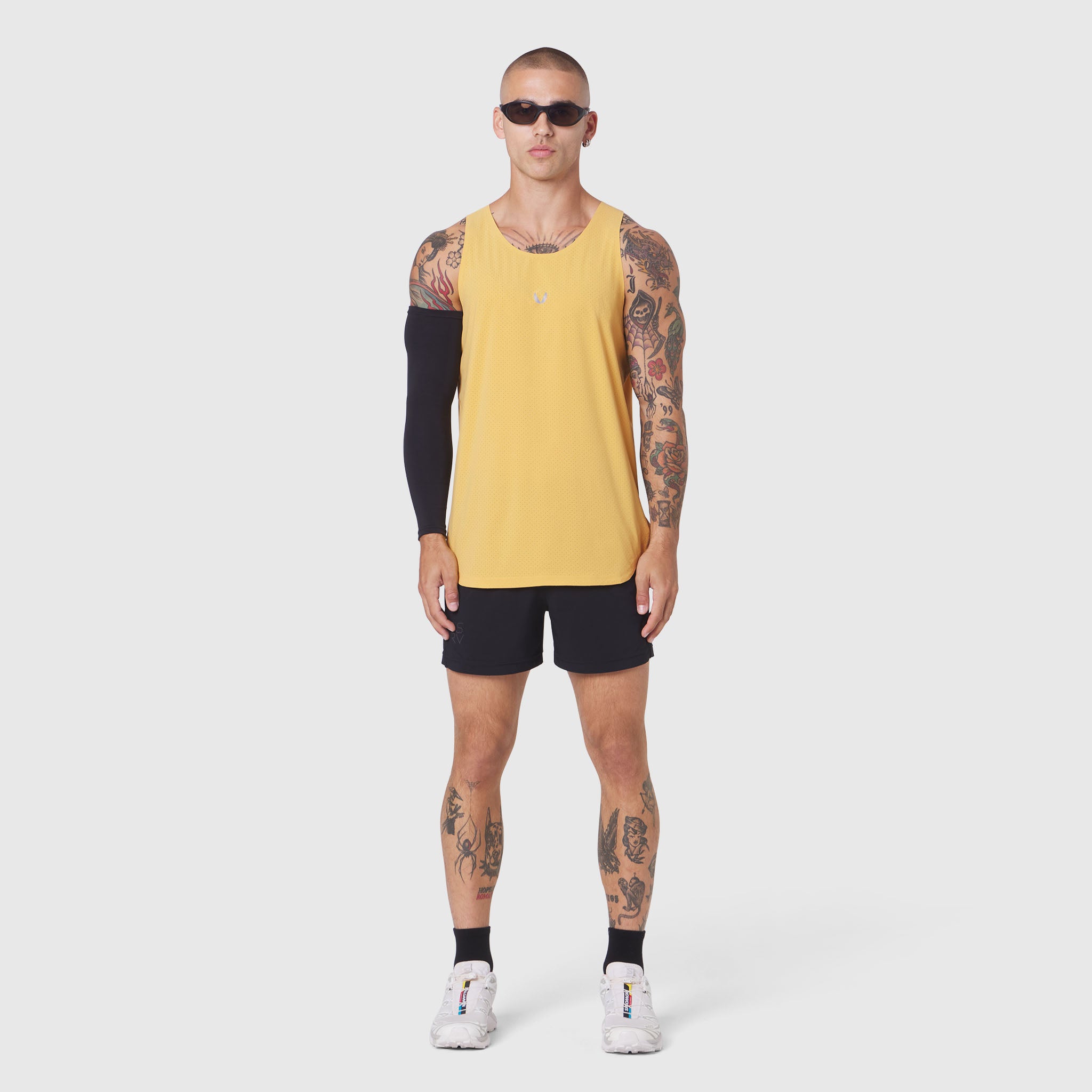 Aerotex Perforated Run Tank in amber yellow worn with black shorts, front view on model