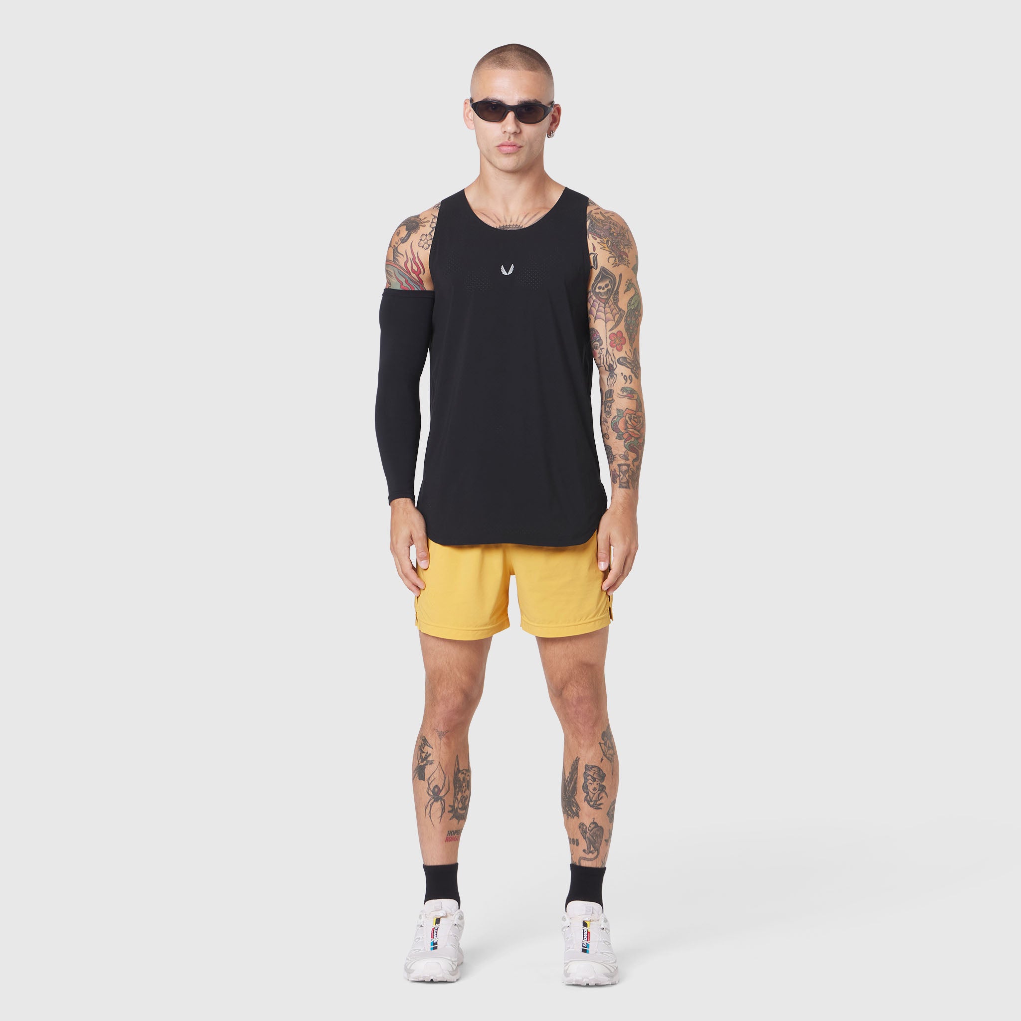 Aerotex Perforated Run Tank in black worn with yellow shorts, front view on model