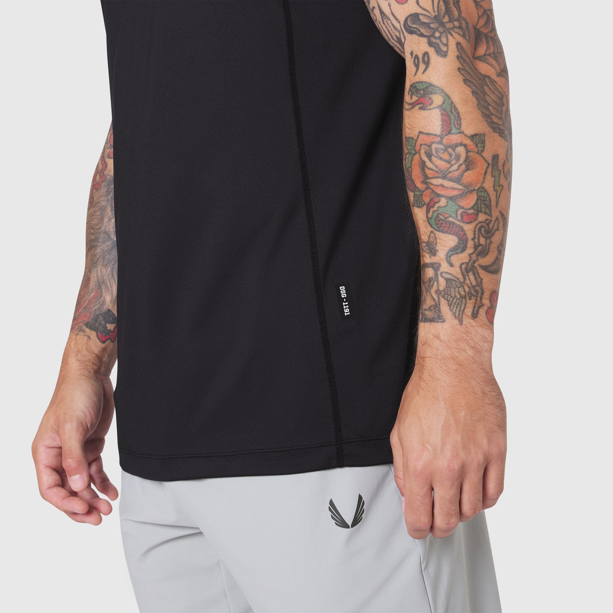 AEROSILVER® UPF50+ Run Tee in black, worn by tattooed model with light gray shorts, side view