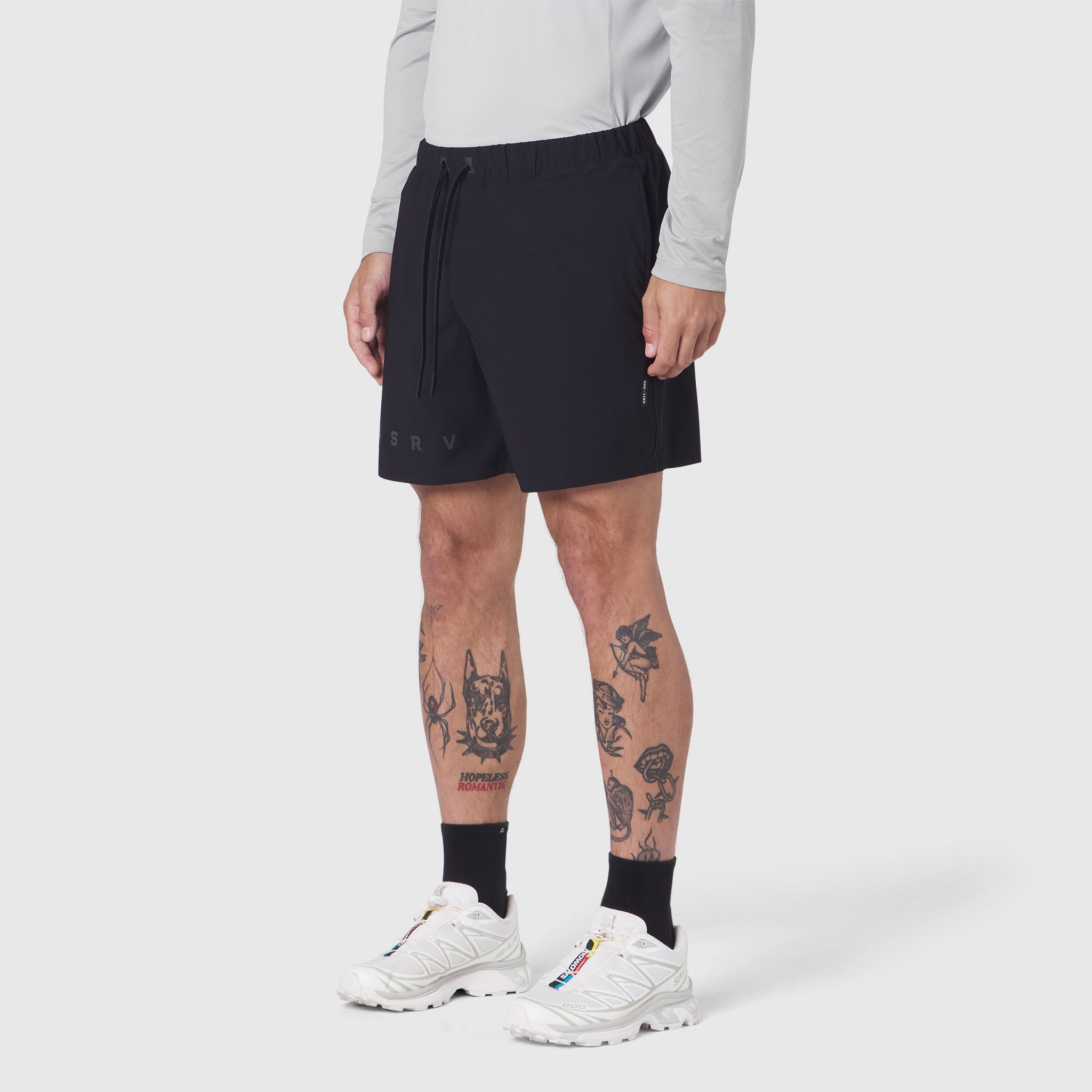 Black Revolutional Training Short worn by model with white sneakers and black socks, front view