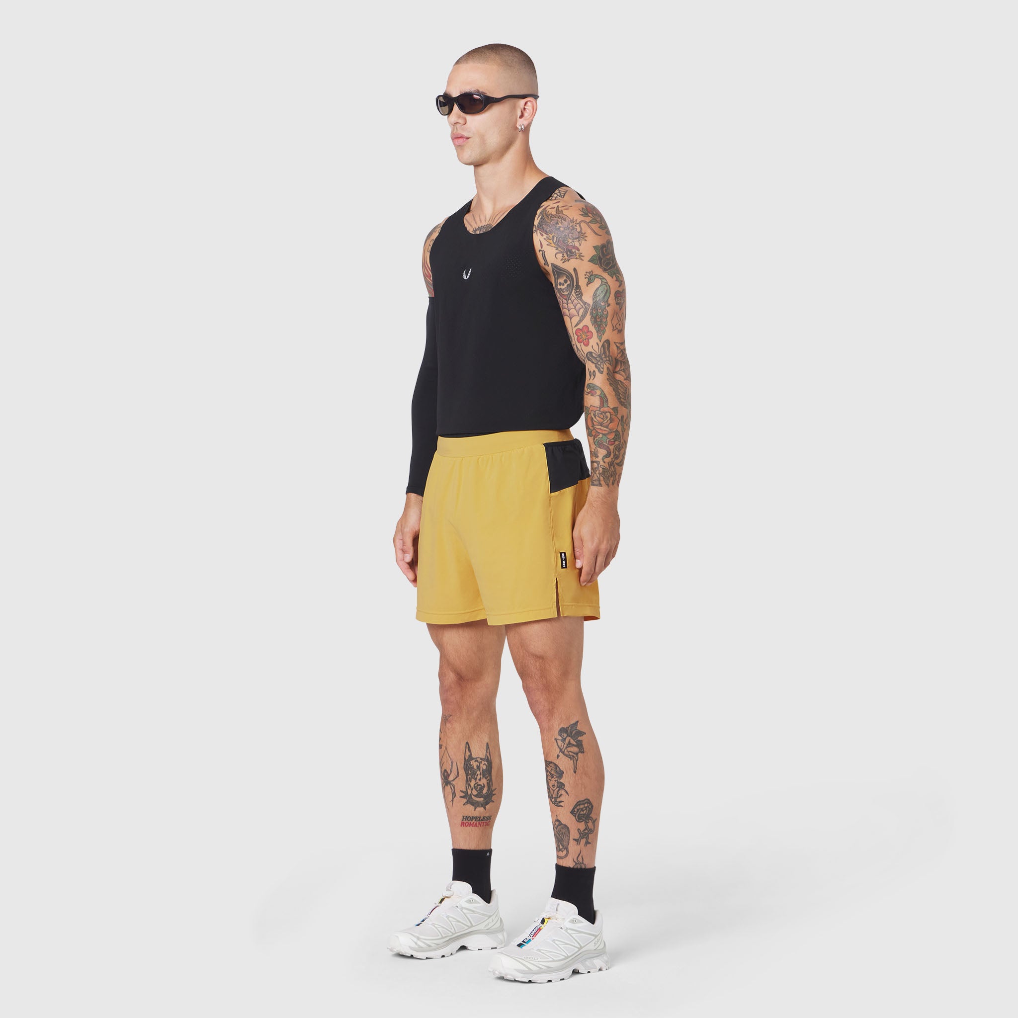 Aerotex™ Distance Run Short in amber yellow, worn by model with black sleeveless top, side view
