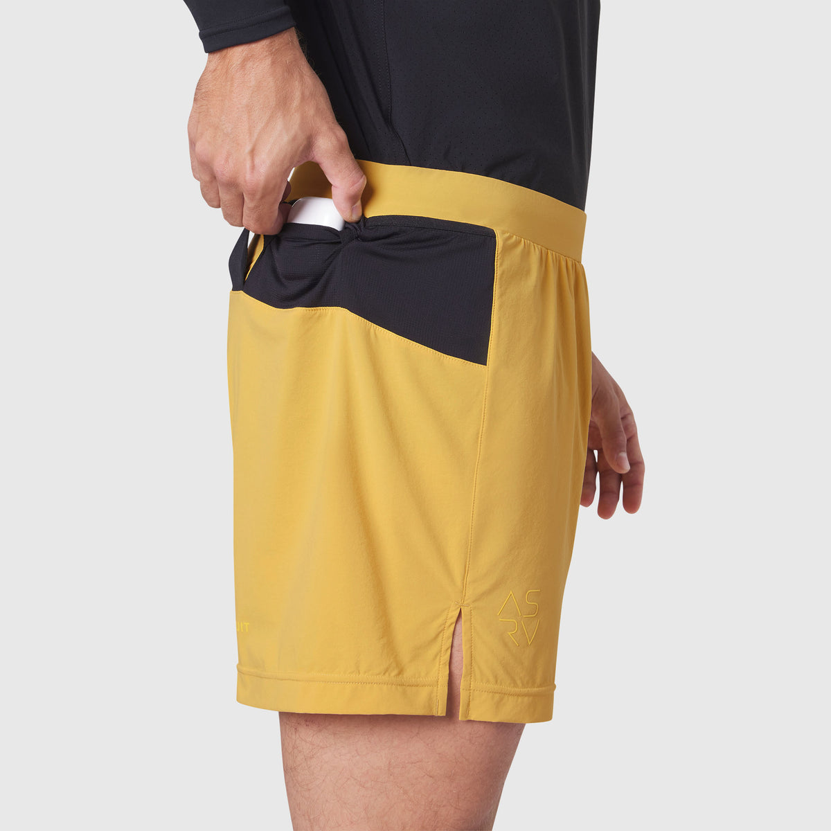 Aerotex Distance Run Short in amber yellow with black pocket detail, worn by model with hand in pocket