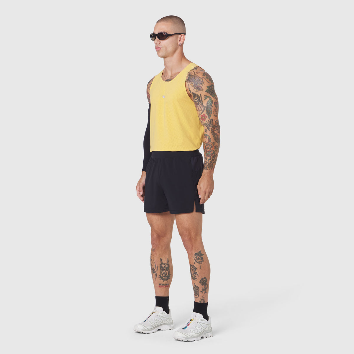 Aerotex Distance Run Short in black worn with yellow tank top, side view