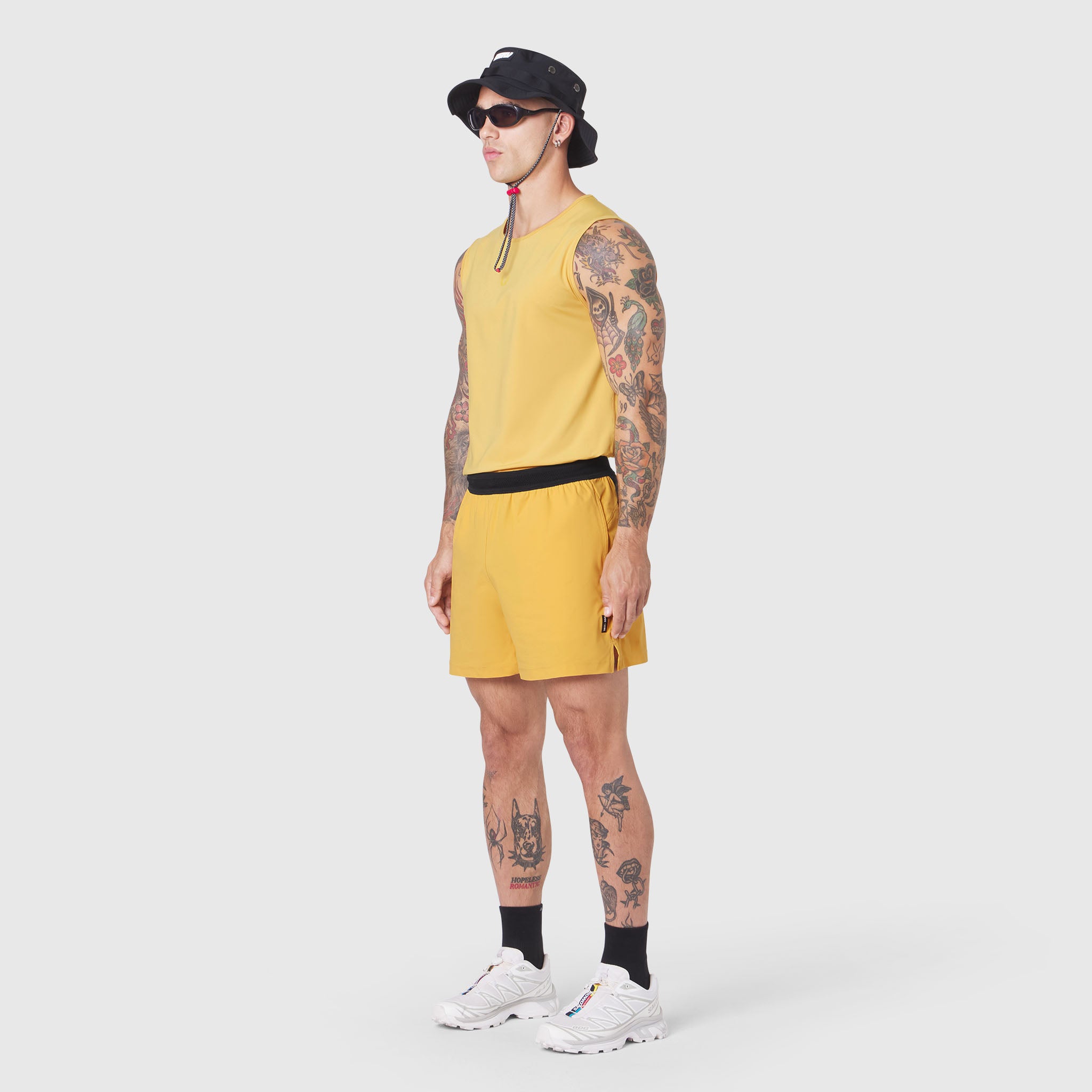 Tetra-Lite 5" Linerless Training Short in amber, worn by model with tank top and sneakers, side view