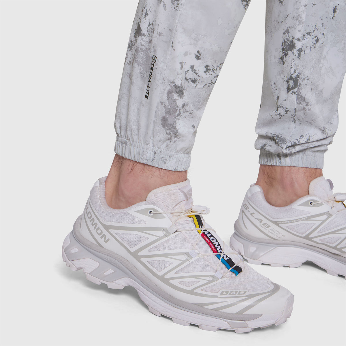 Model wearing white Tetra-Lite Training Jogger with white sneakers and colorful lace detail