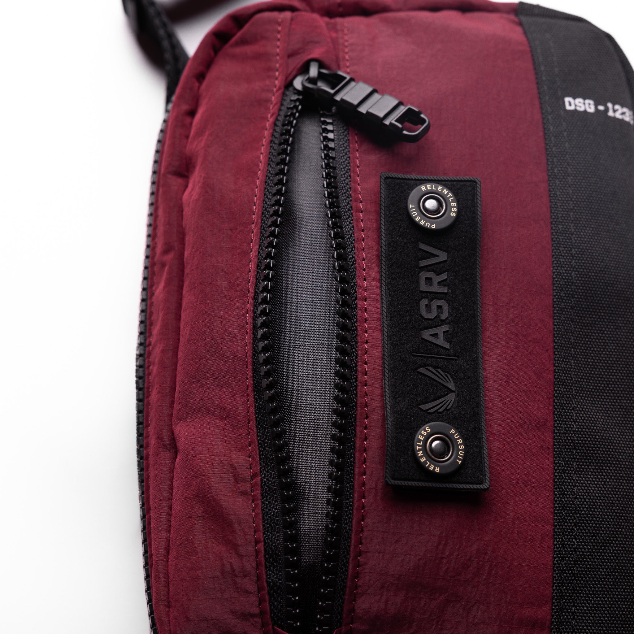 1231 Ripstop Crossbody Bag in Crimson, being worn, detail view of zipper and branding