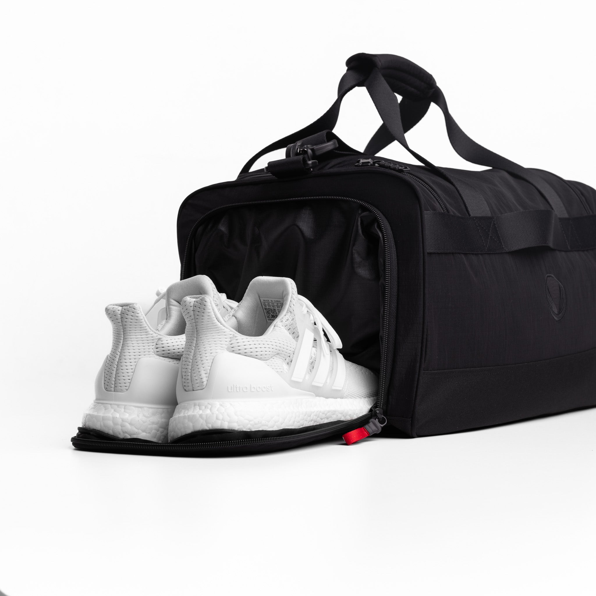 Flatlay 1234 Ripstop Duffle Bag in black with white sneakers, front view