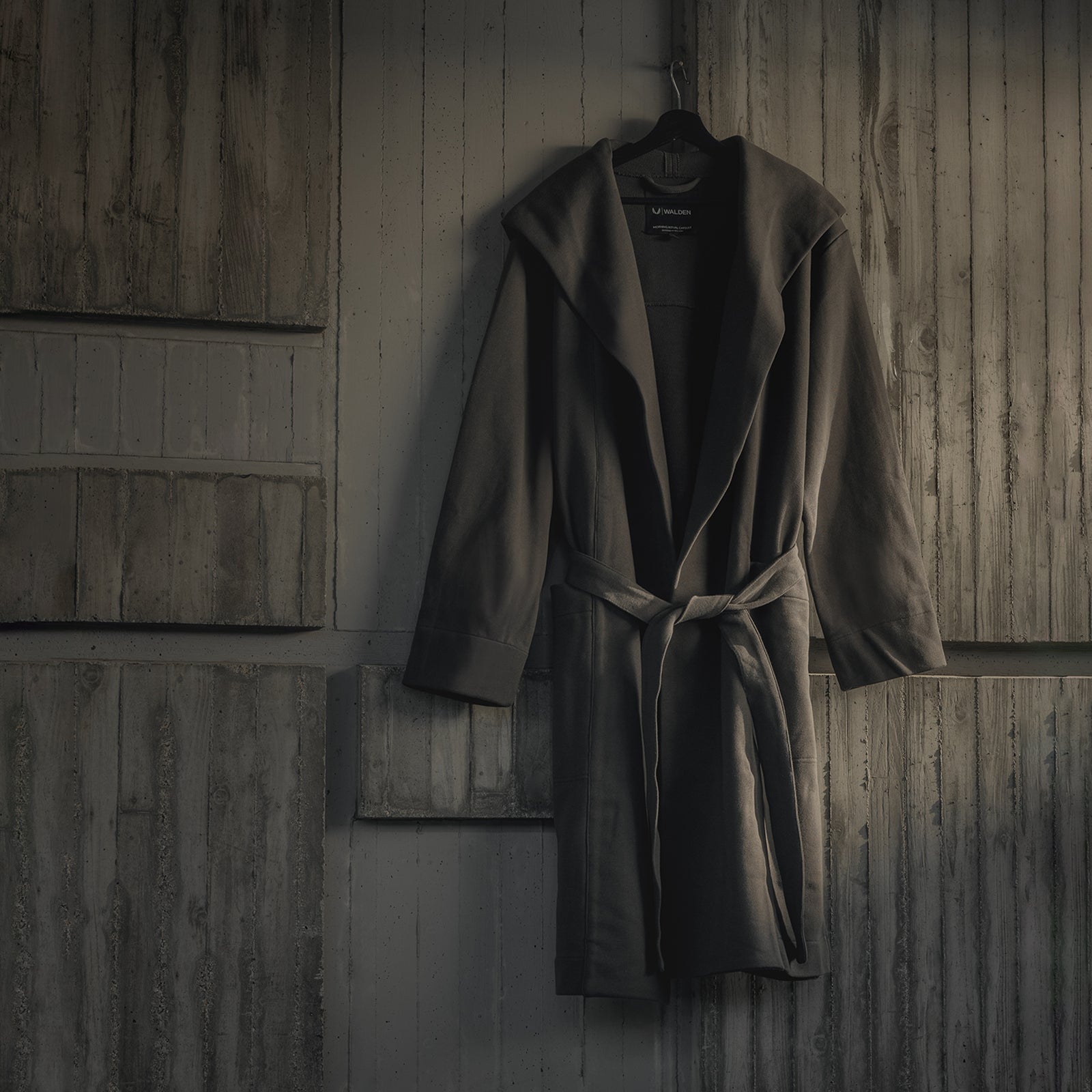 ASRV Heavyweight Robe in carbon, hung on hanger against wooden wall