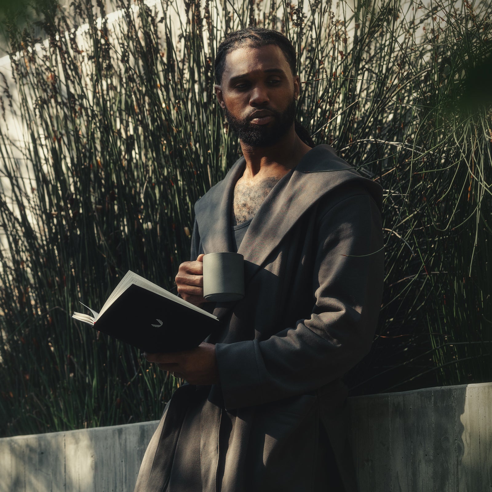 Man holding ASRV x Walden journal and mug outdoors among tall grasses