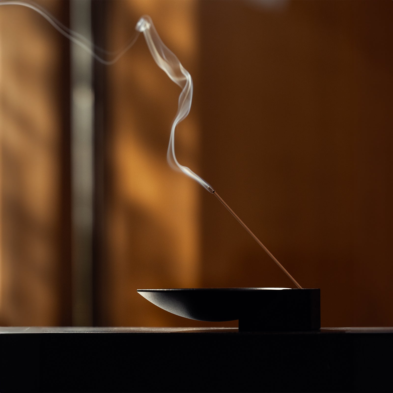 Flatlay of ASRV x Walden Block Incense Holder in black with burning incense stick