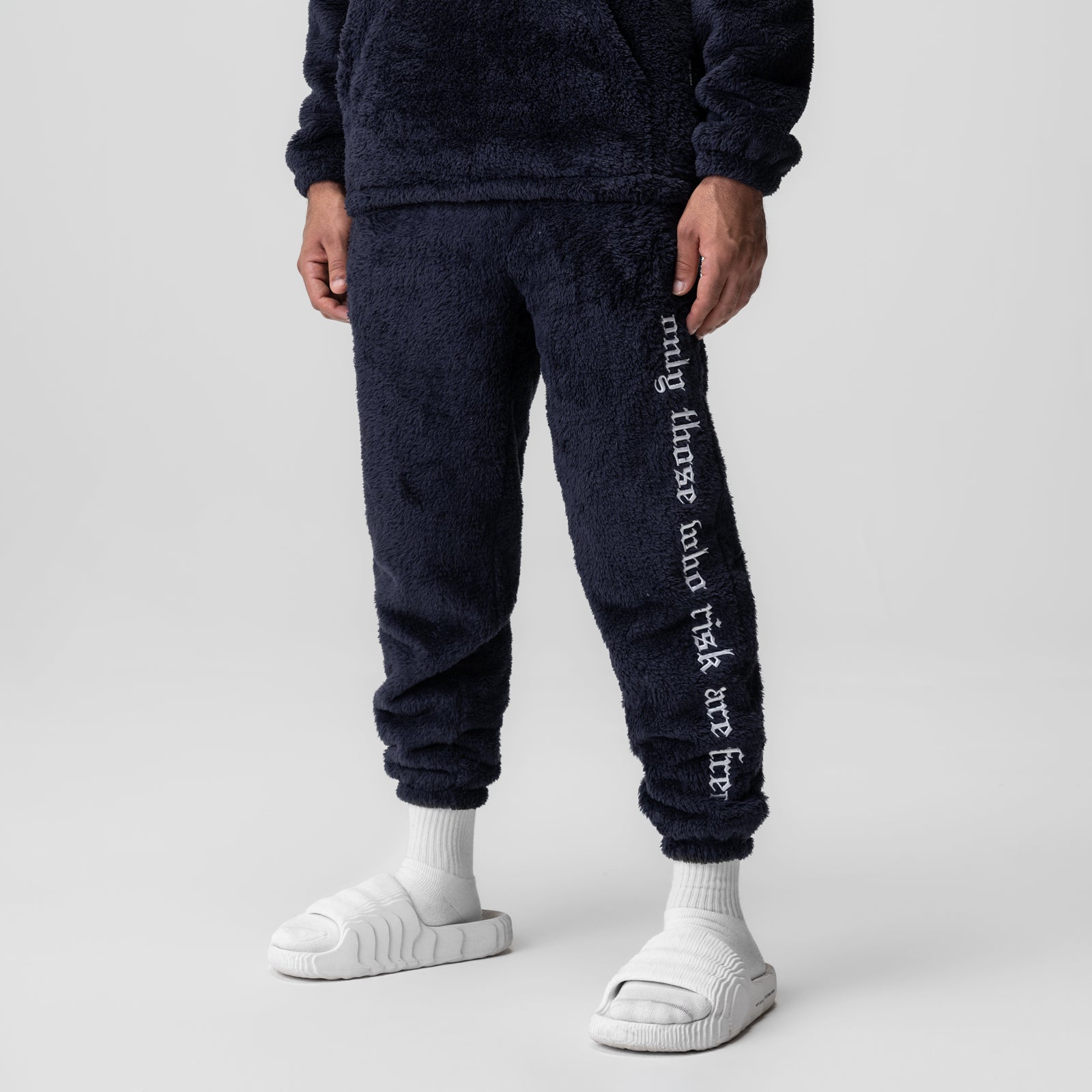 Sherpa Recovery Sweats in navy with white text down the leg, worn with white socks and slides
