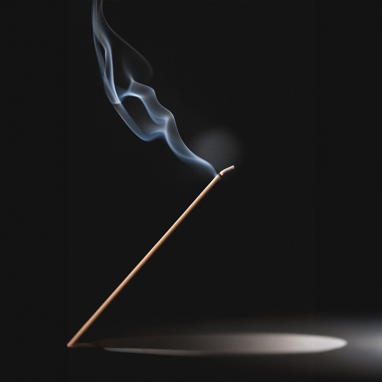 Flatlay of ASRV x Walden Pure Sandalwood incense stick with smoke against black background