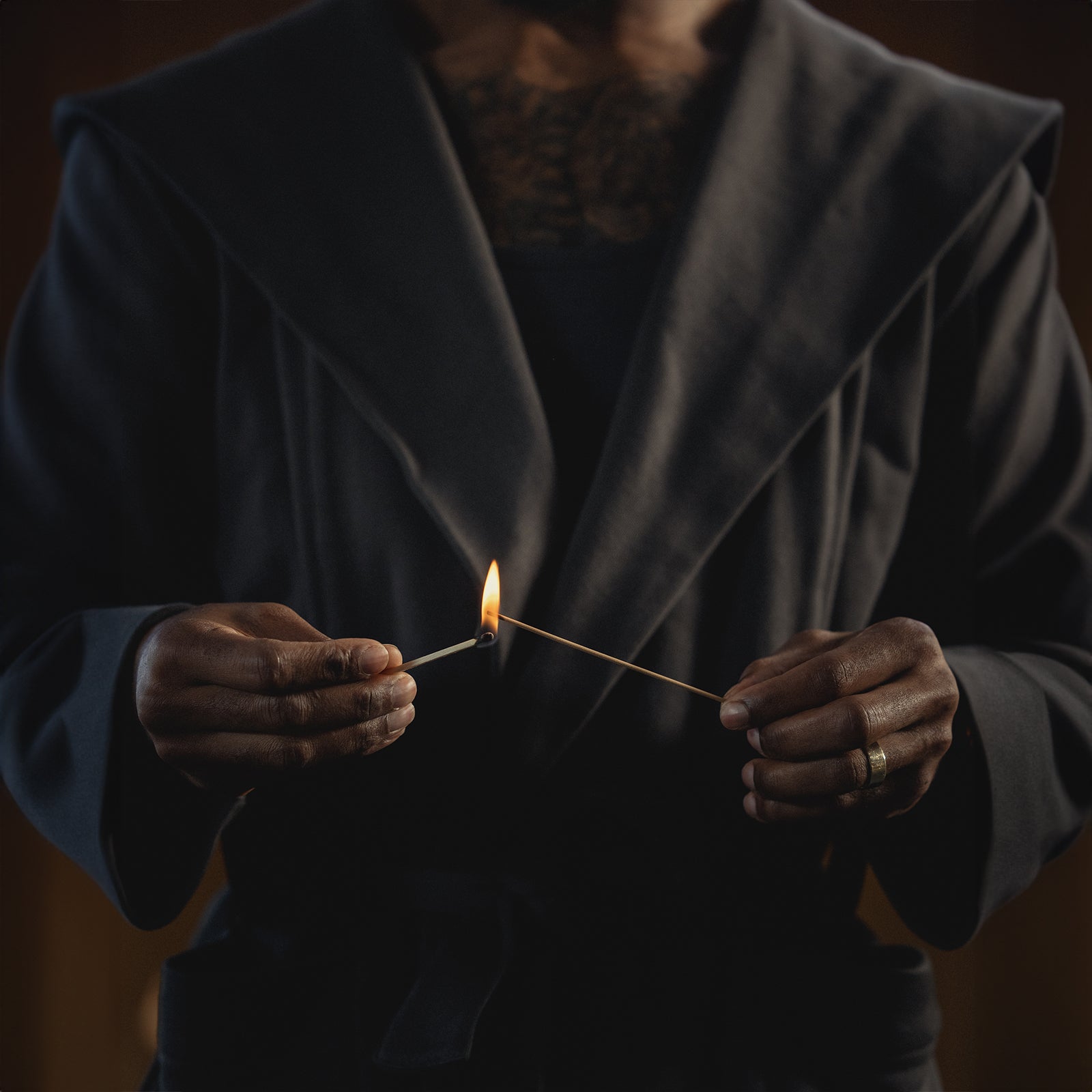Person in dark blazer holding two lit matches together, ASRV x Walden Block Incense Holder