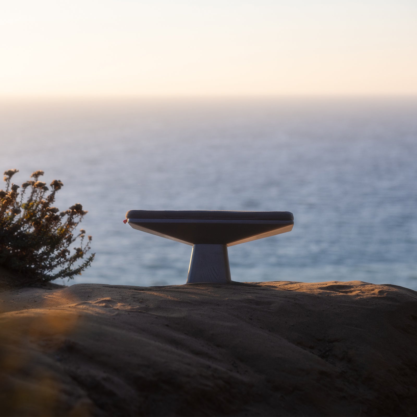 ASRV x Walden Meditation Bench in black, displayed on rocky coastal landscape at sunset