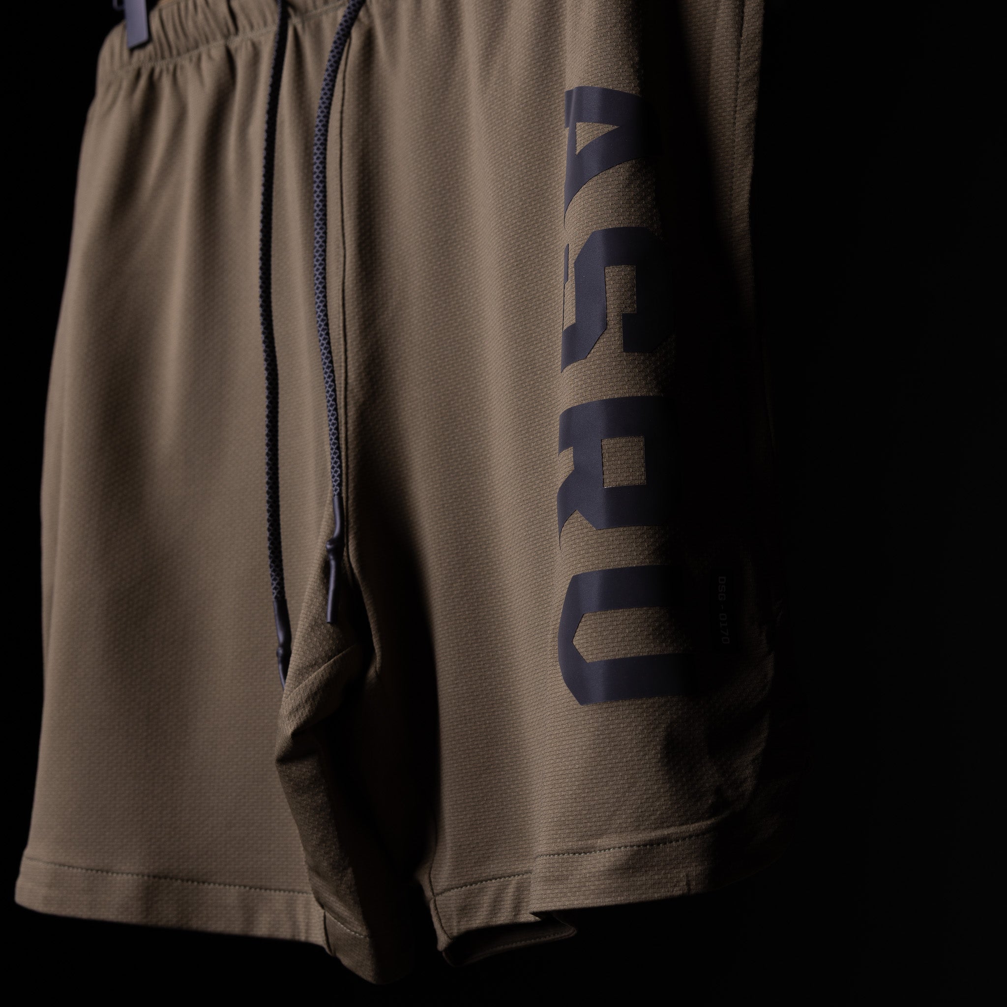 SP'19 7" Linerless Short in khaki tan with navy branding, worn detail shot