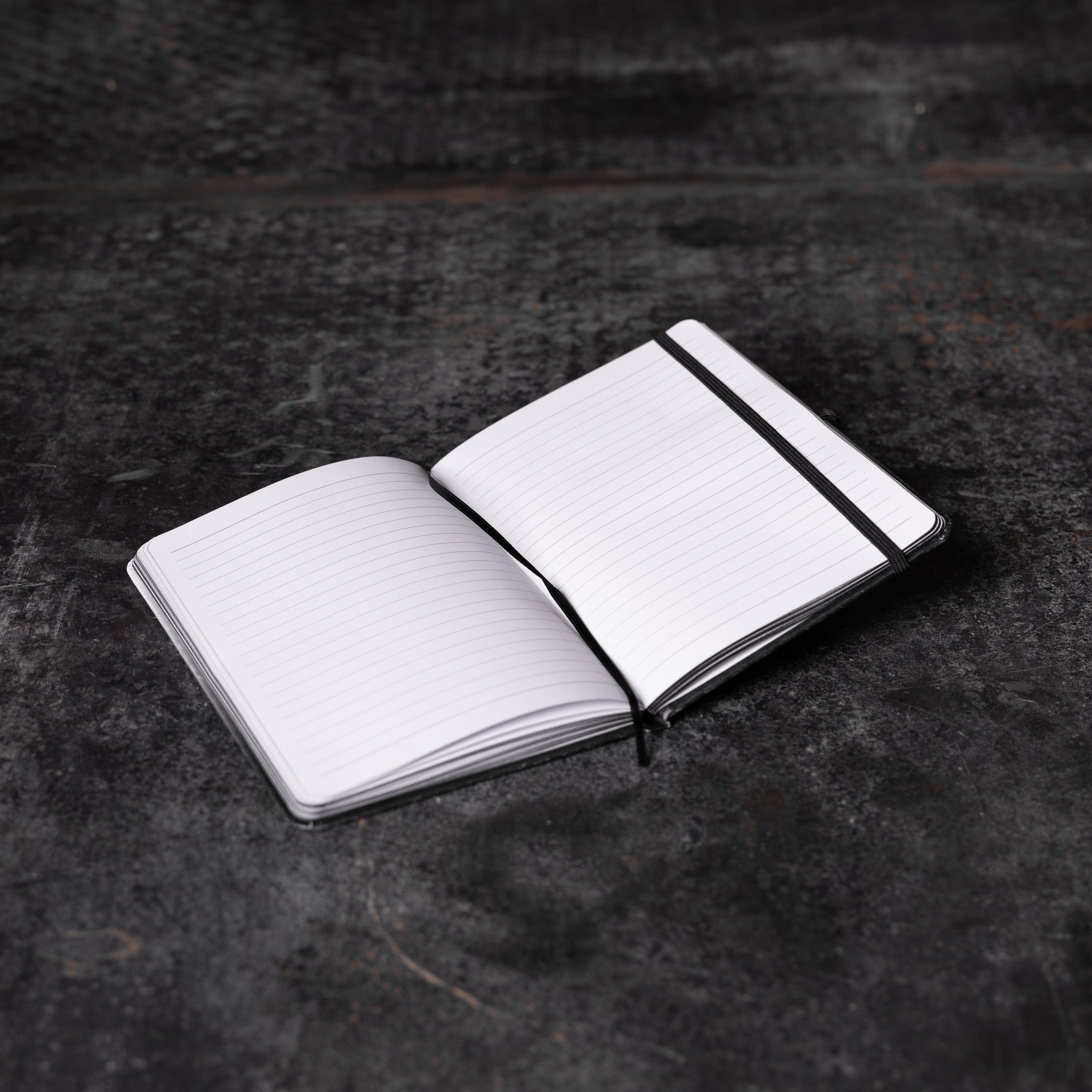 Flatlay of SM'22 OTWR Notebook in white and black, open pages view on dark textured surface