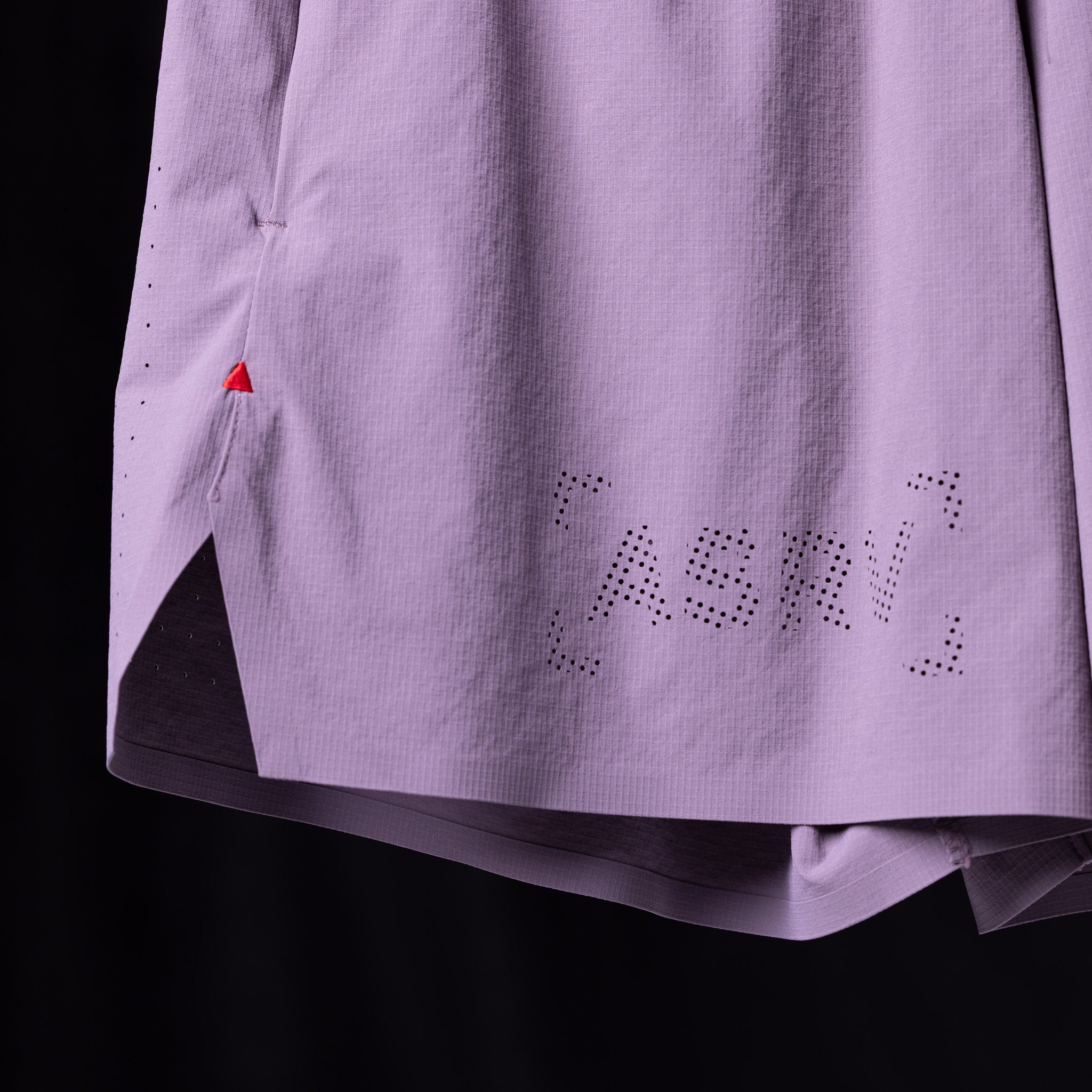 WN'23 6" Perforated Short in lavender, laid flat detail shot showing perforated text design