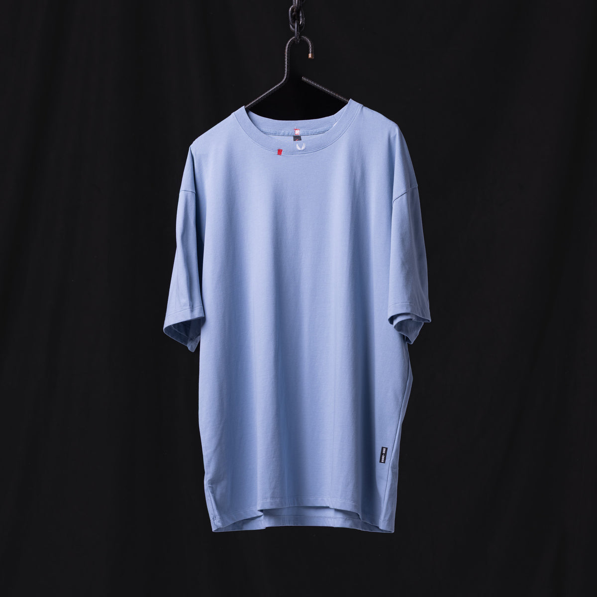 Light blue distressed tee on hanger against dark background, front view