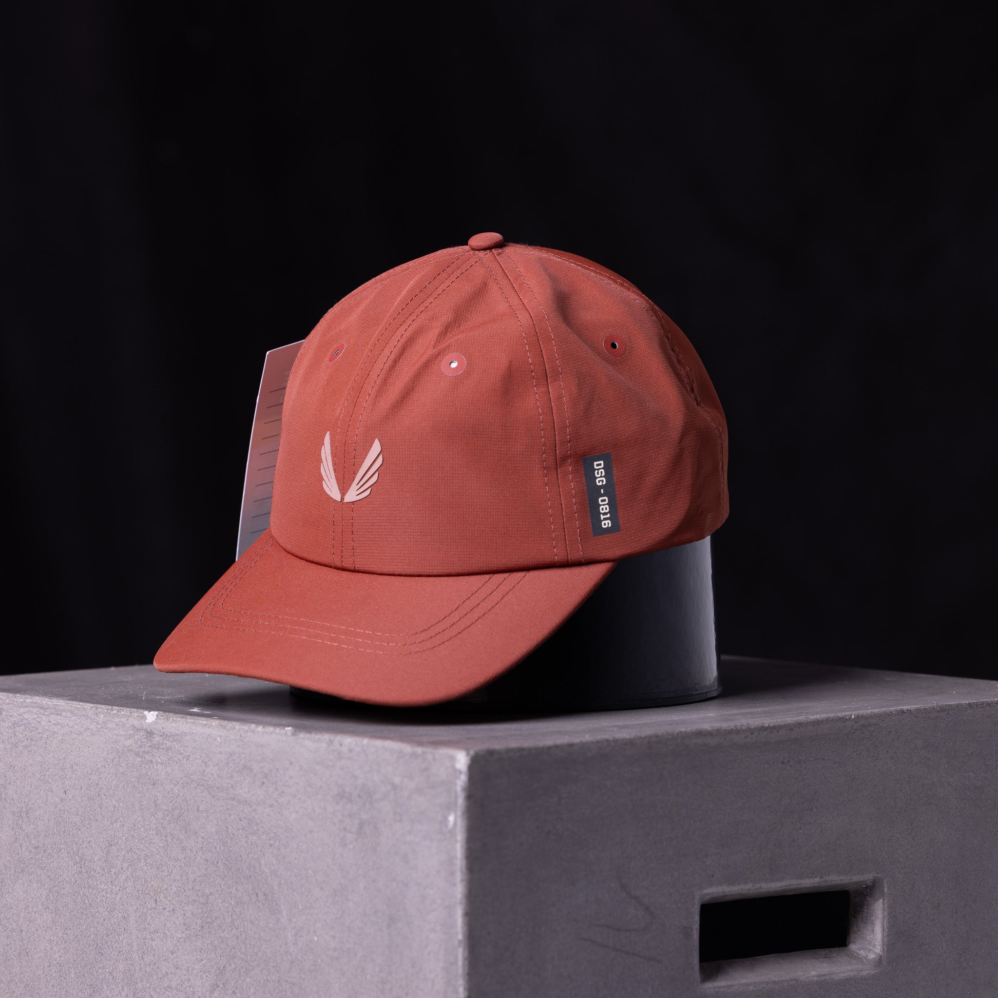 flatlay SP'23 Hybrid Sport Cap in rust red with white feather logo, front view