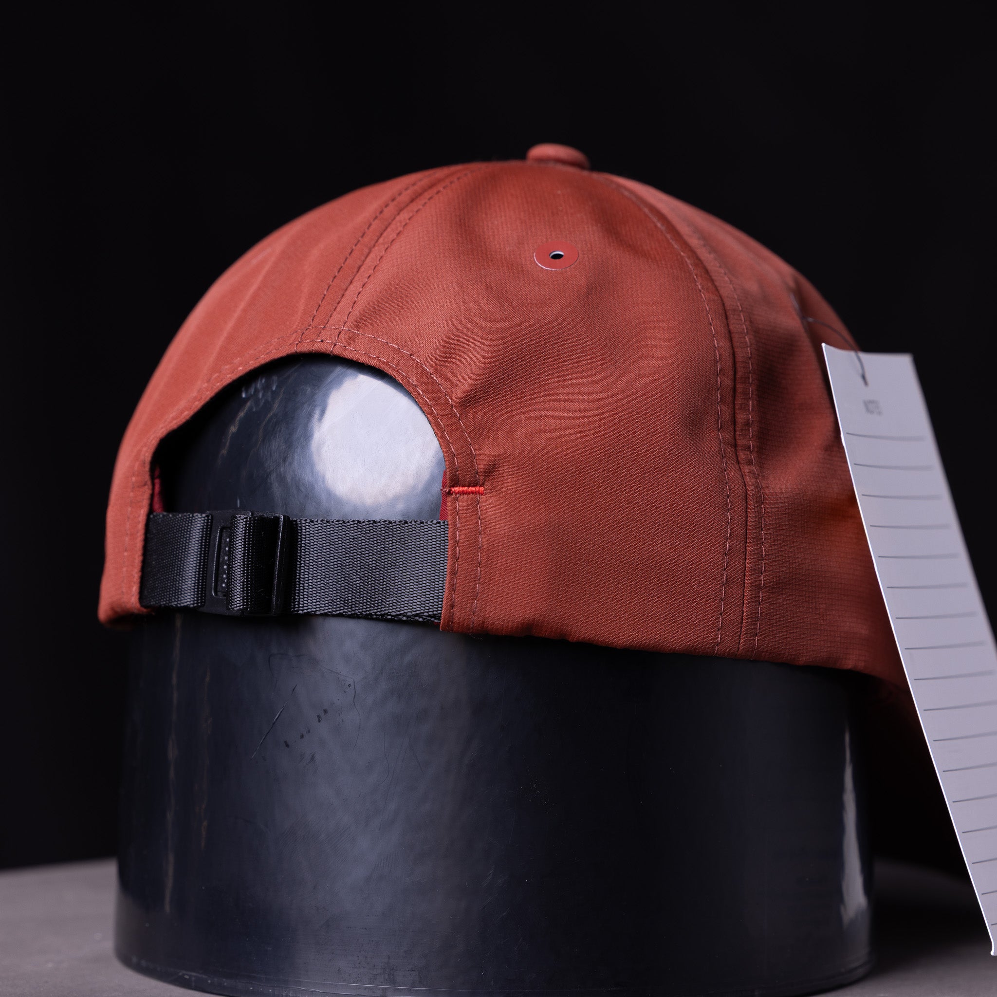 SP'23 Hybrid Sport Cap in rust red, displayed on mannequin head with black adjustable strap