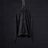 Black contrast thread hoodie displayed on hanger against dark brick wall