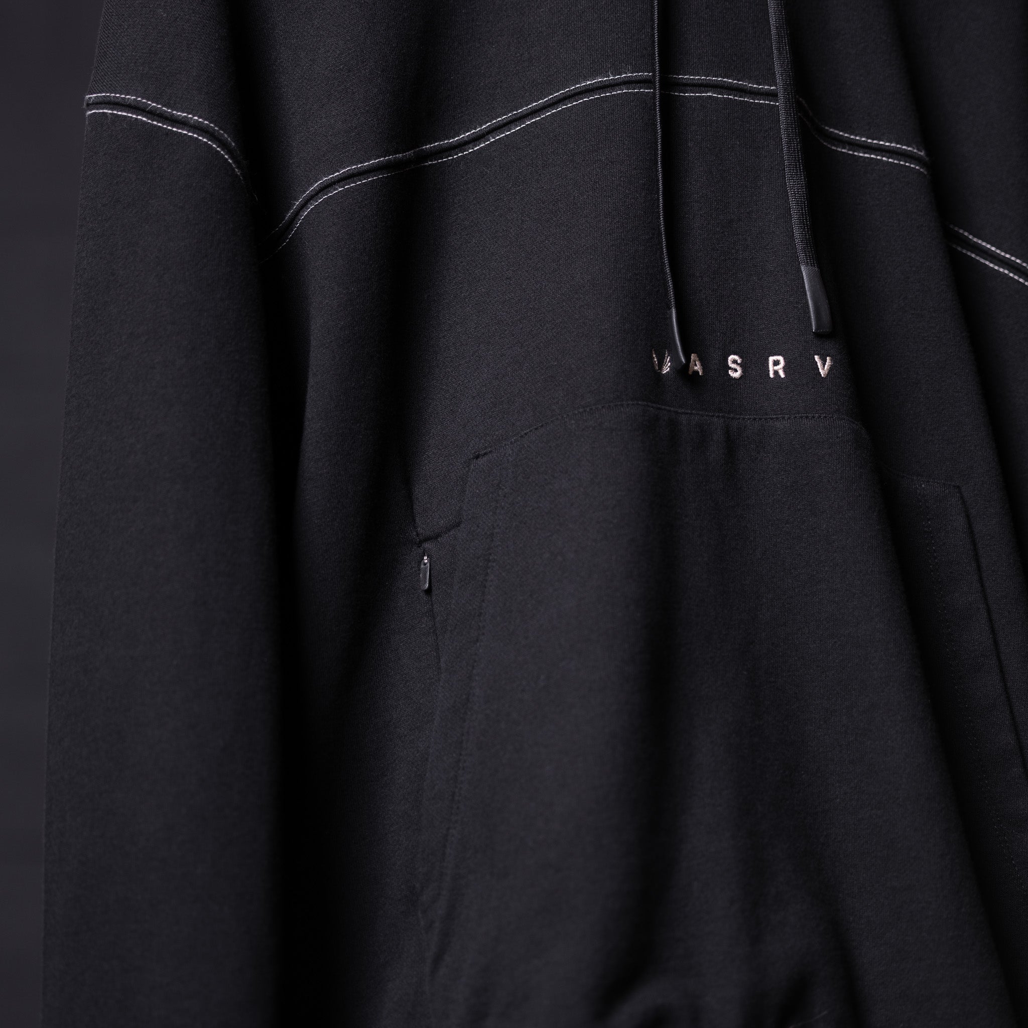 FA'20 Contrast Thread Hoodie in black with white stitching detail, draped fabric closeup